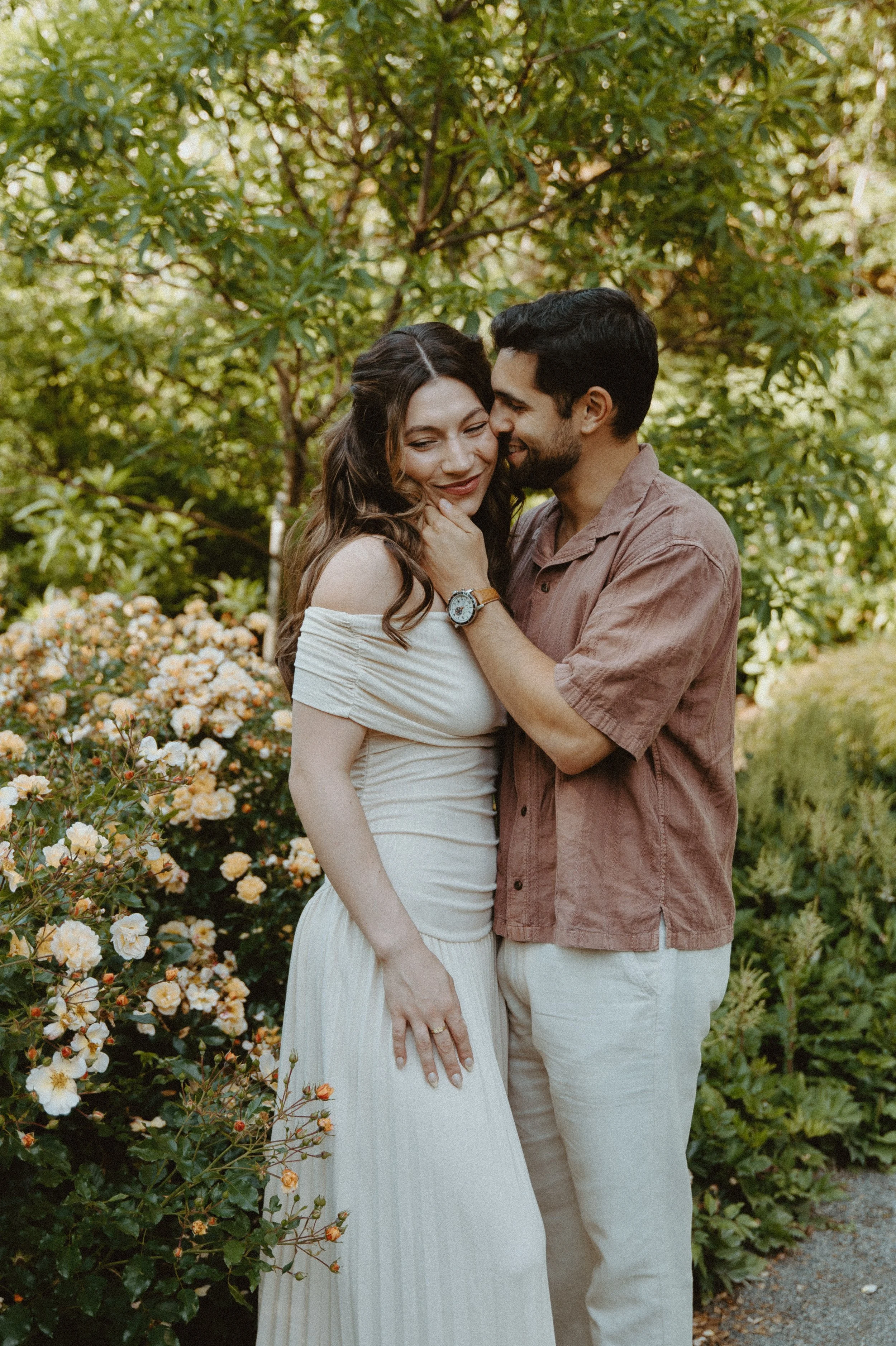 Woman smiling as partner gently touches her face + candid couple moment + Seattle engagement session + natural light photography