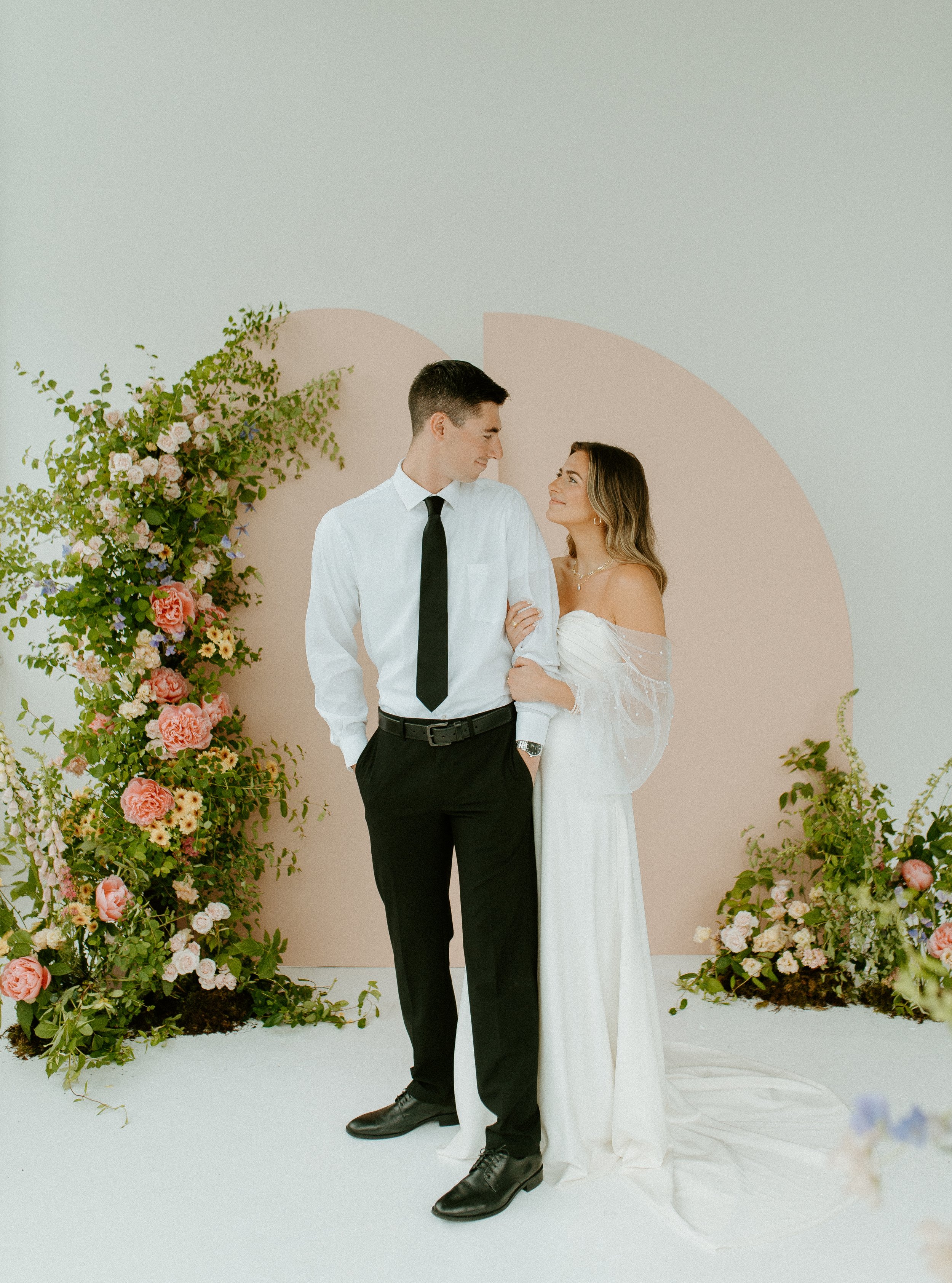 elegant wedding couple posing in Seattle studio with soft pink and green florals