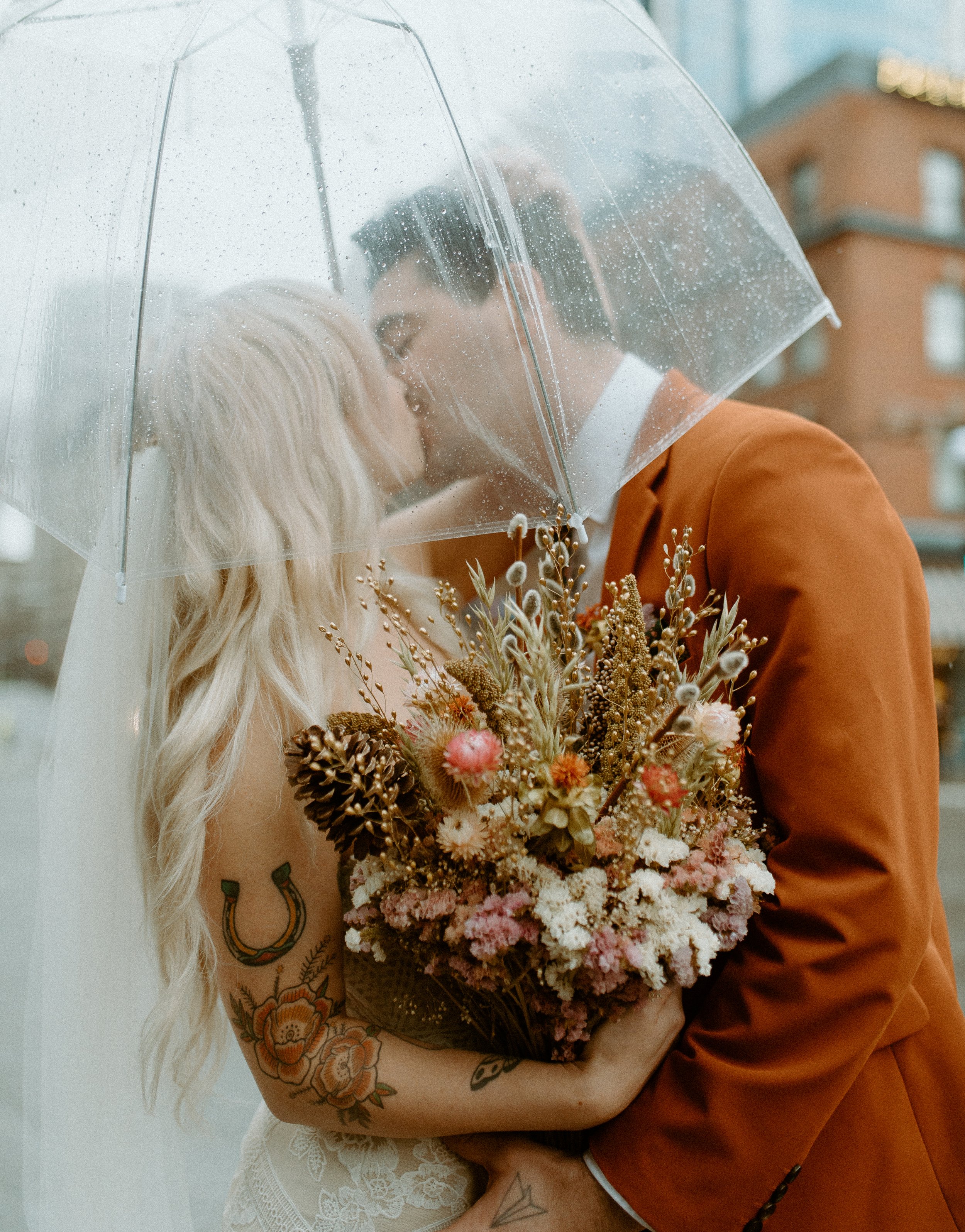 Bride and groom sharing a kiss under a clear umbrella during a rainy Seattle elopement