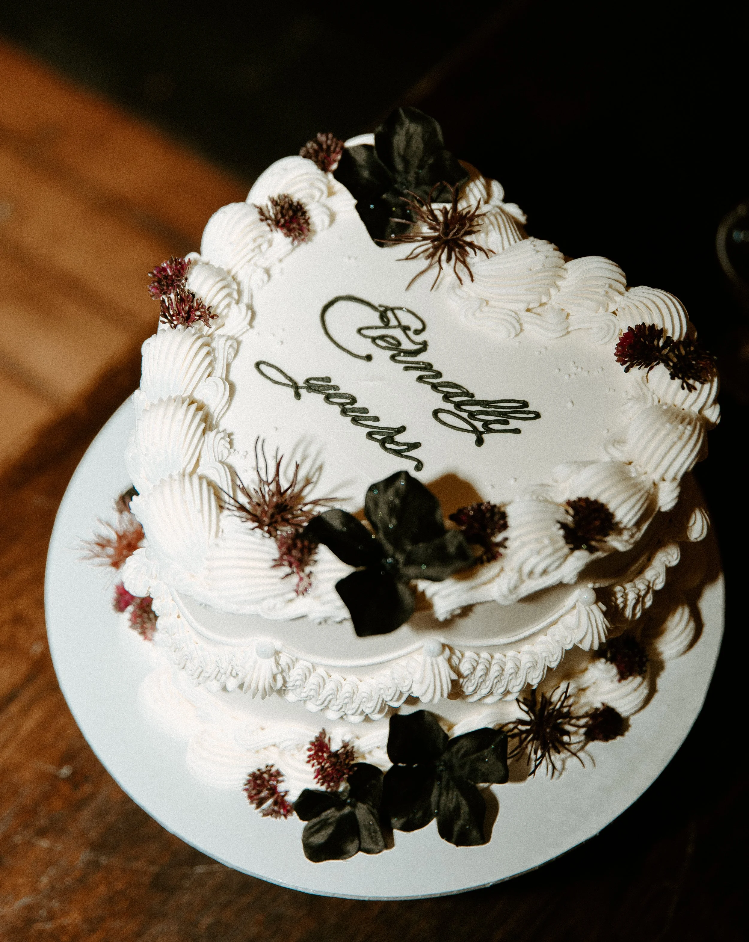 Elegant white wedding cake with dark florals and vintage piping displayed at a romantic Seattle boat wedding reception