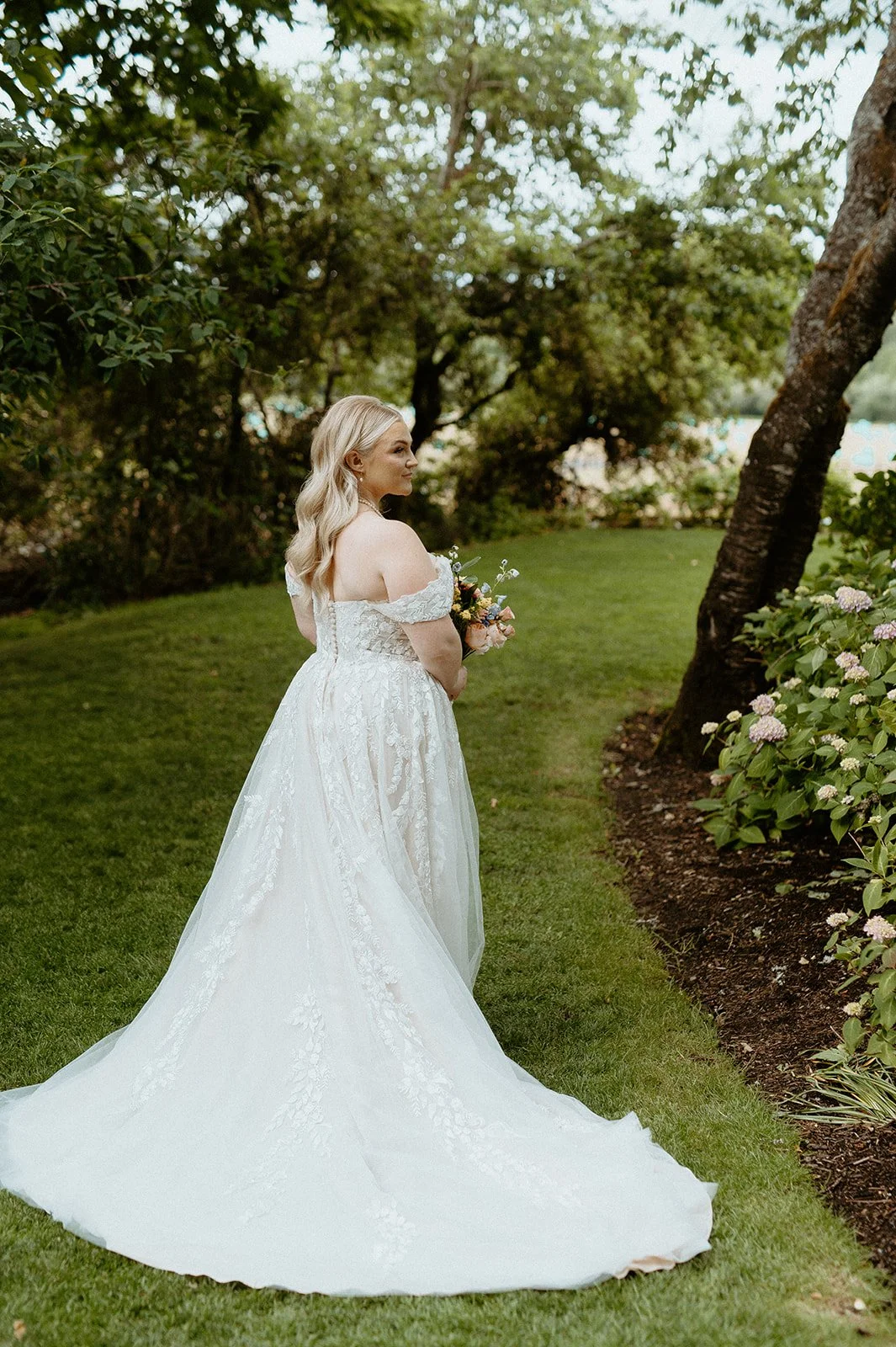 Bride in lace wedding dress standing in garden at Kelley Farm wedding venue in Washington
