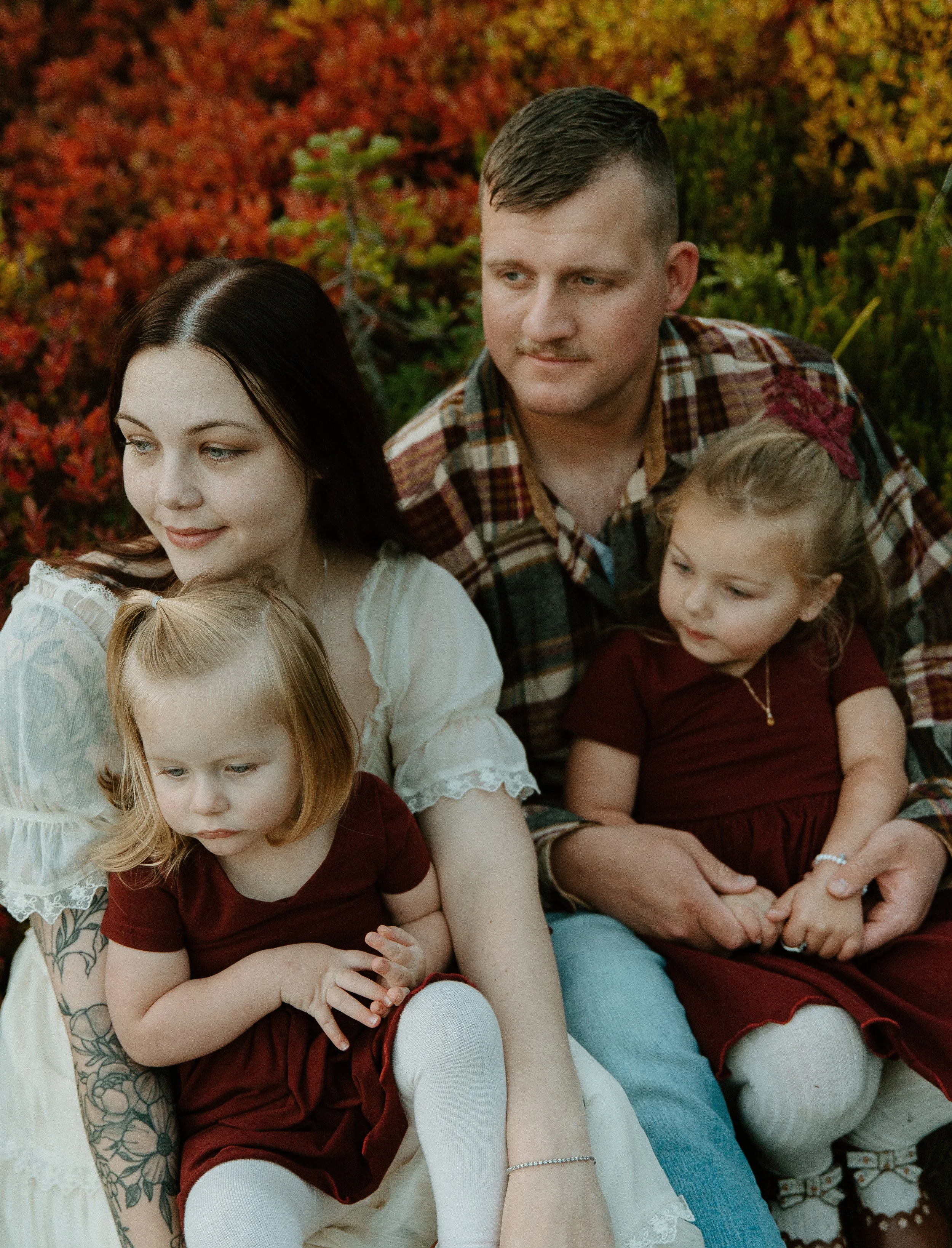     Parents cuddling with their two young daughters surrounded by vibrant autumn colors at Mount Rainier