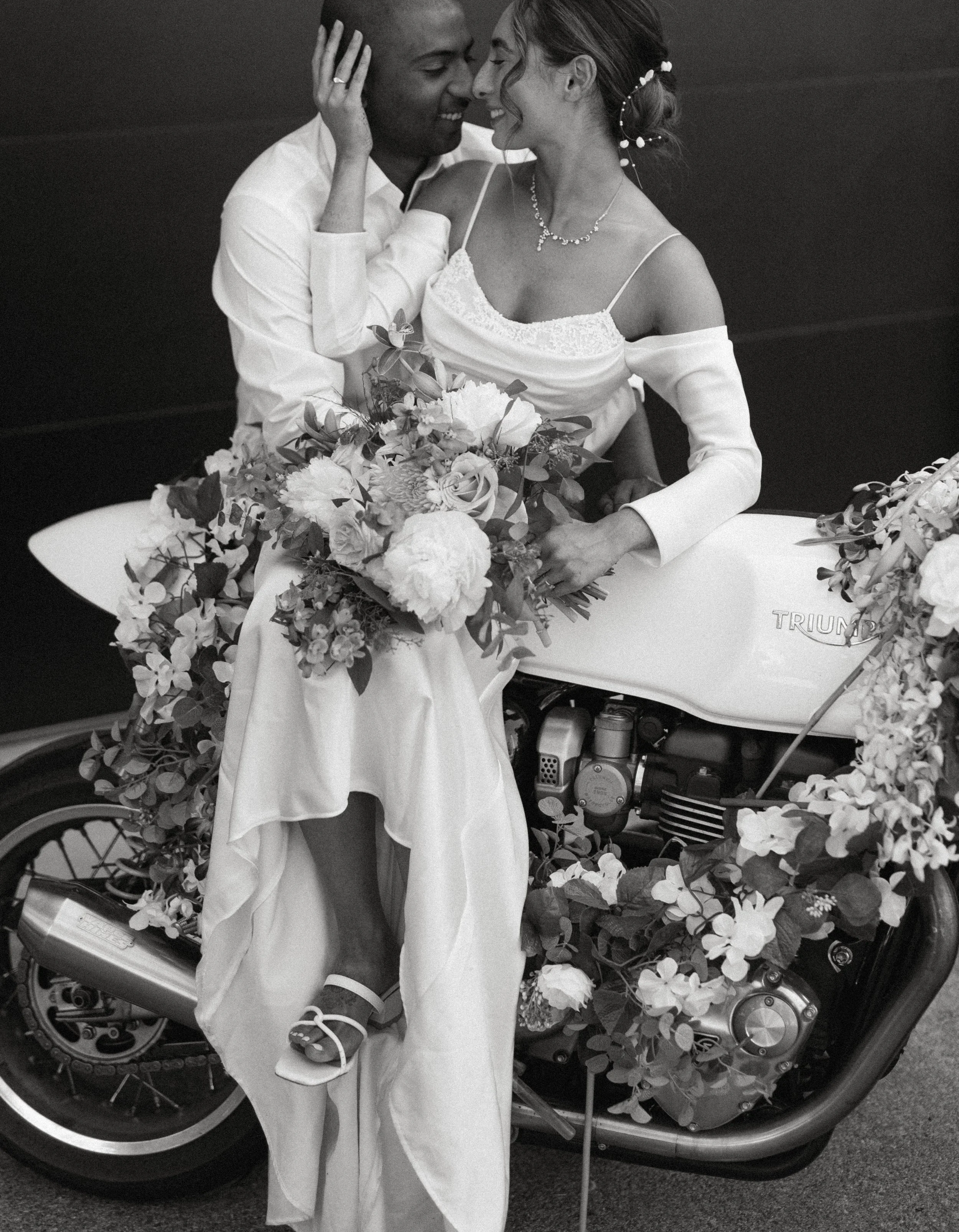 Romantic black and white portrait of newlyweds sitting on motorcycle with flowers at Seattle wedding