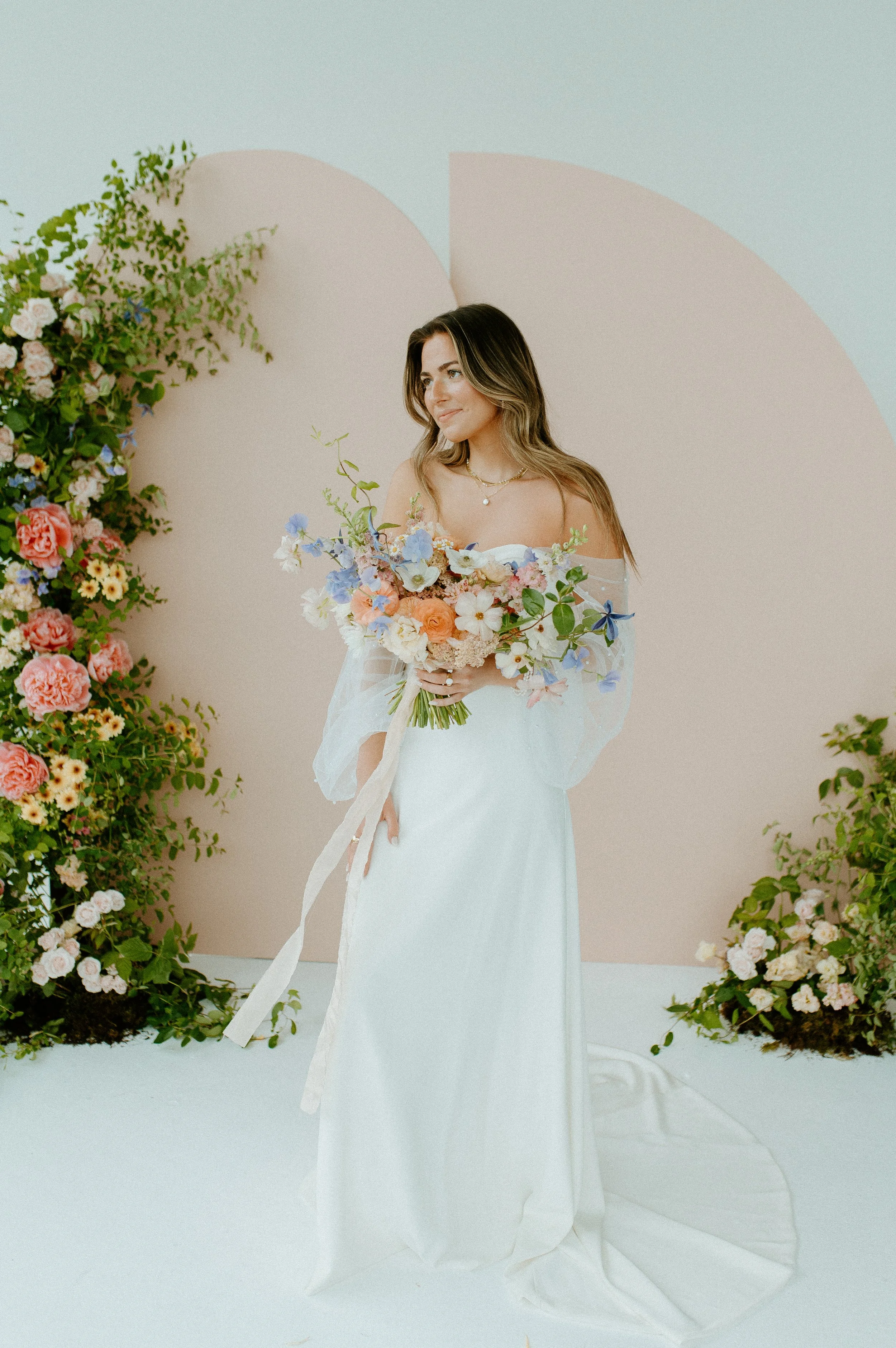 bride standing by floral installation in natural light Seattle studio bridal session