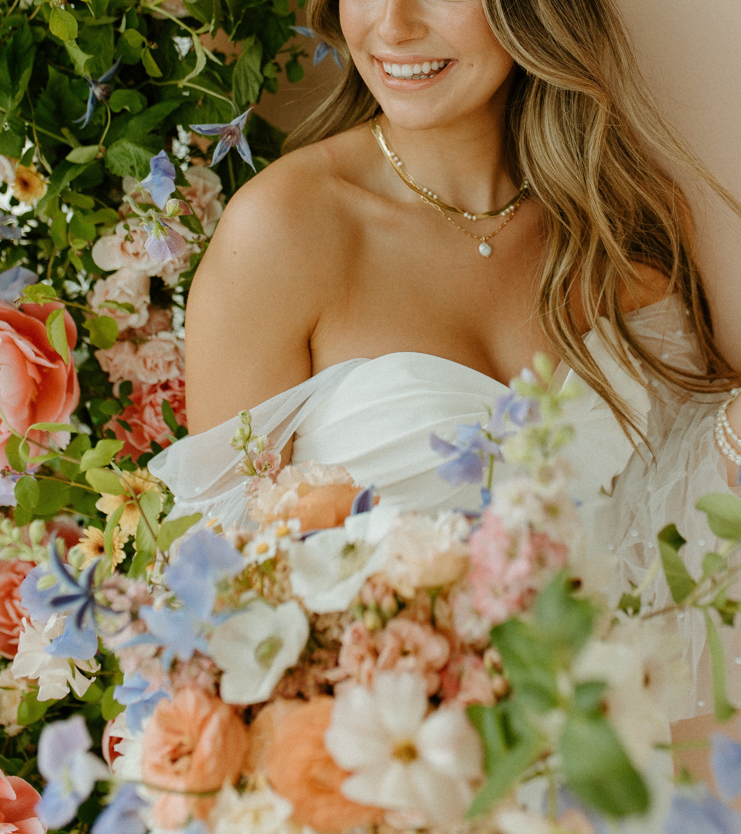 bride holding colorful bouquet in Seattle studio bridal shoot with soft floral backdrop