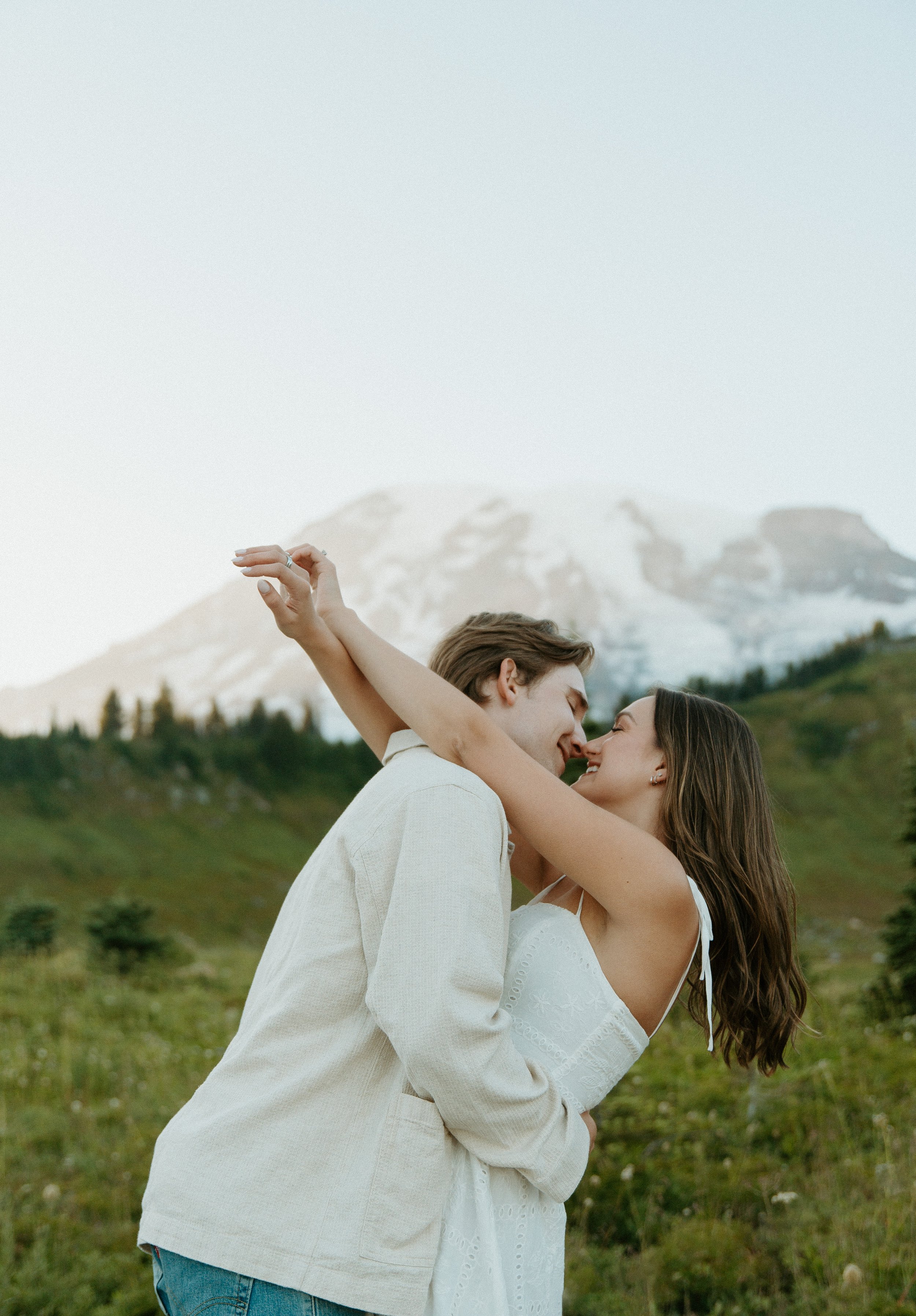 Couple dancing together in a wildflower meadow during their summer Mount Rainier engagement session