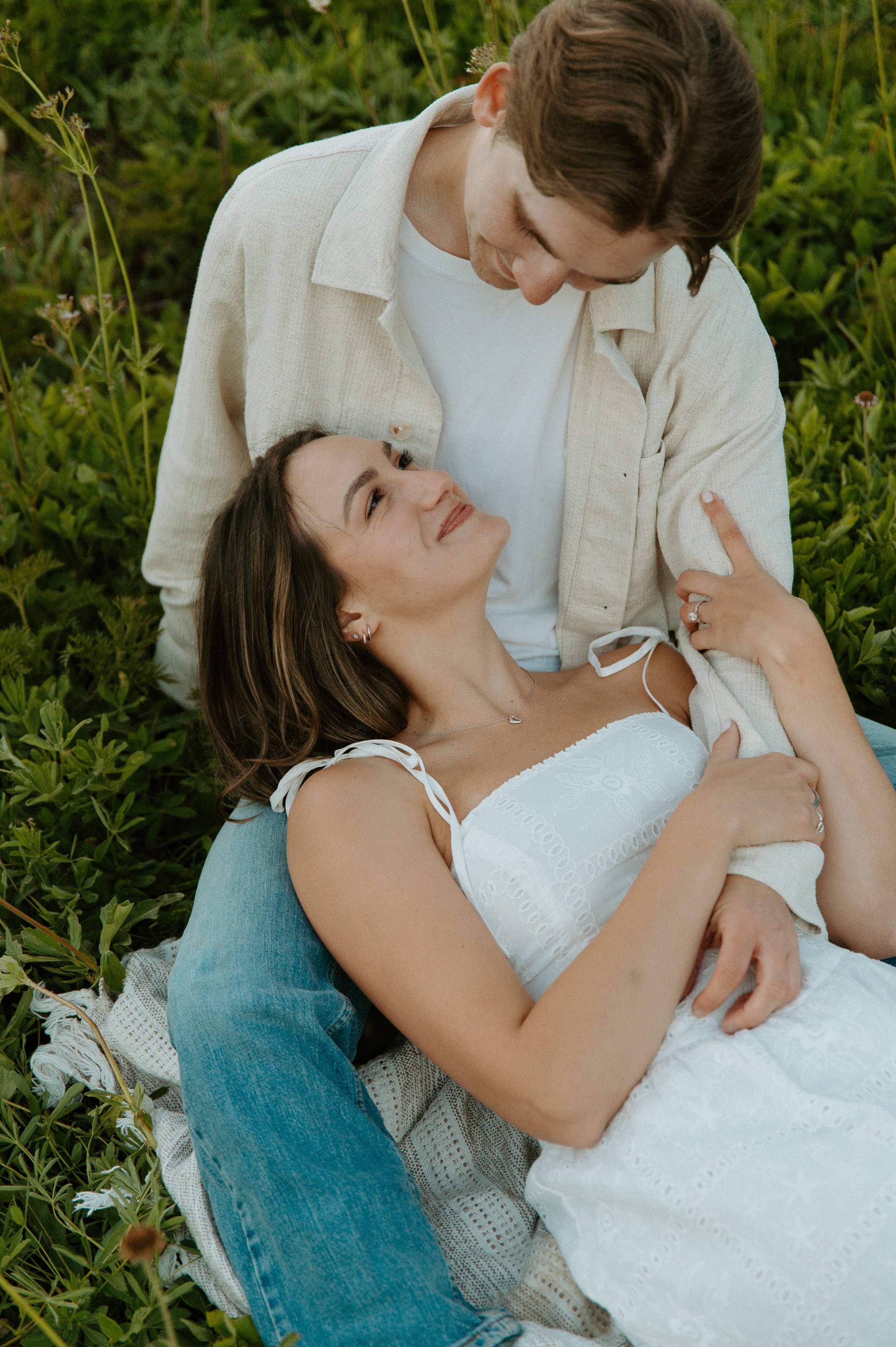 Engaged couple cuddling together in a green wildflower meadow during their Mount Rainier engagement photos