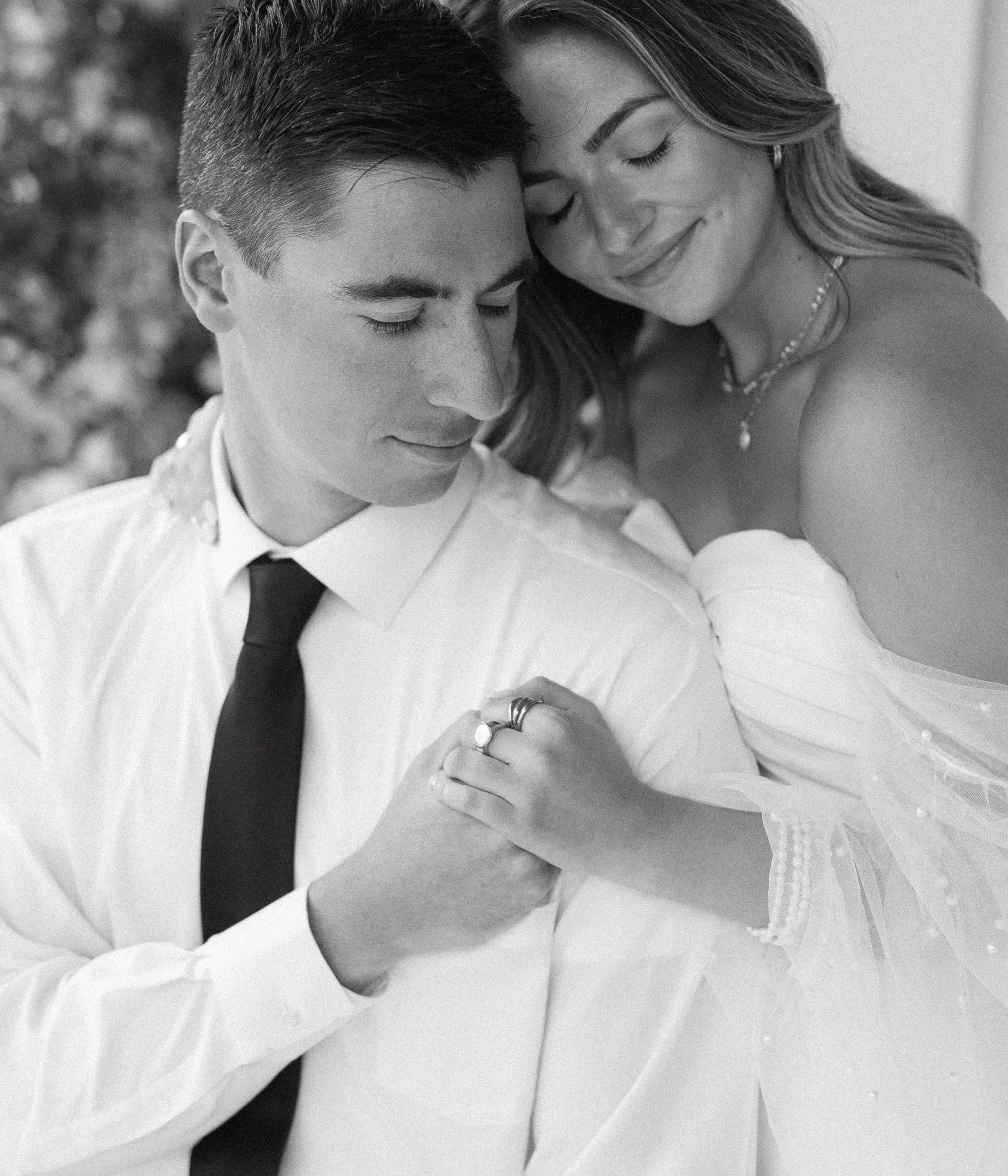 romantic black and white portrait of bride and groom embracing in studio
