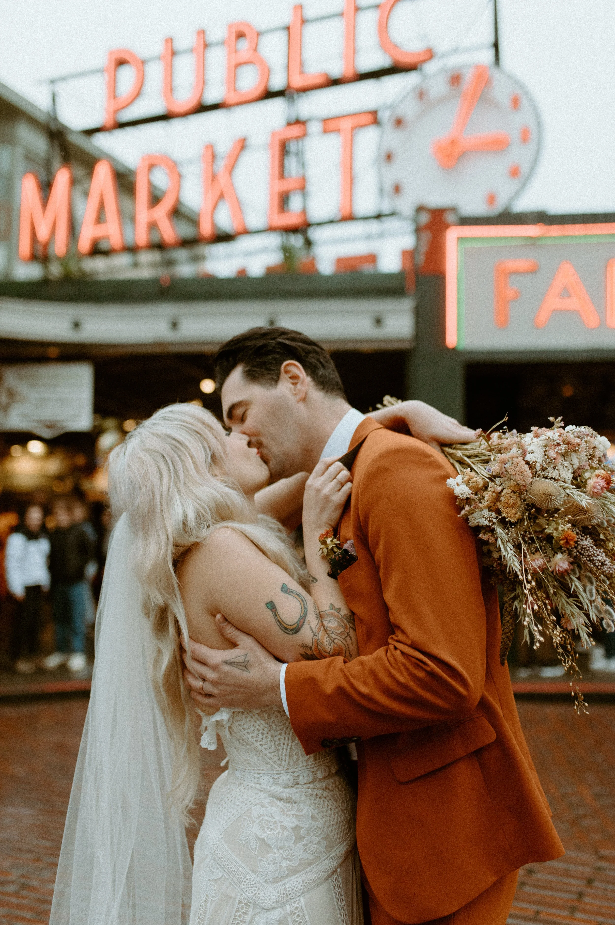 Bride and groom kissing in front of Pike Place Market during a Seattle elopement