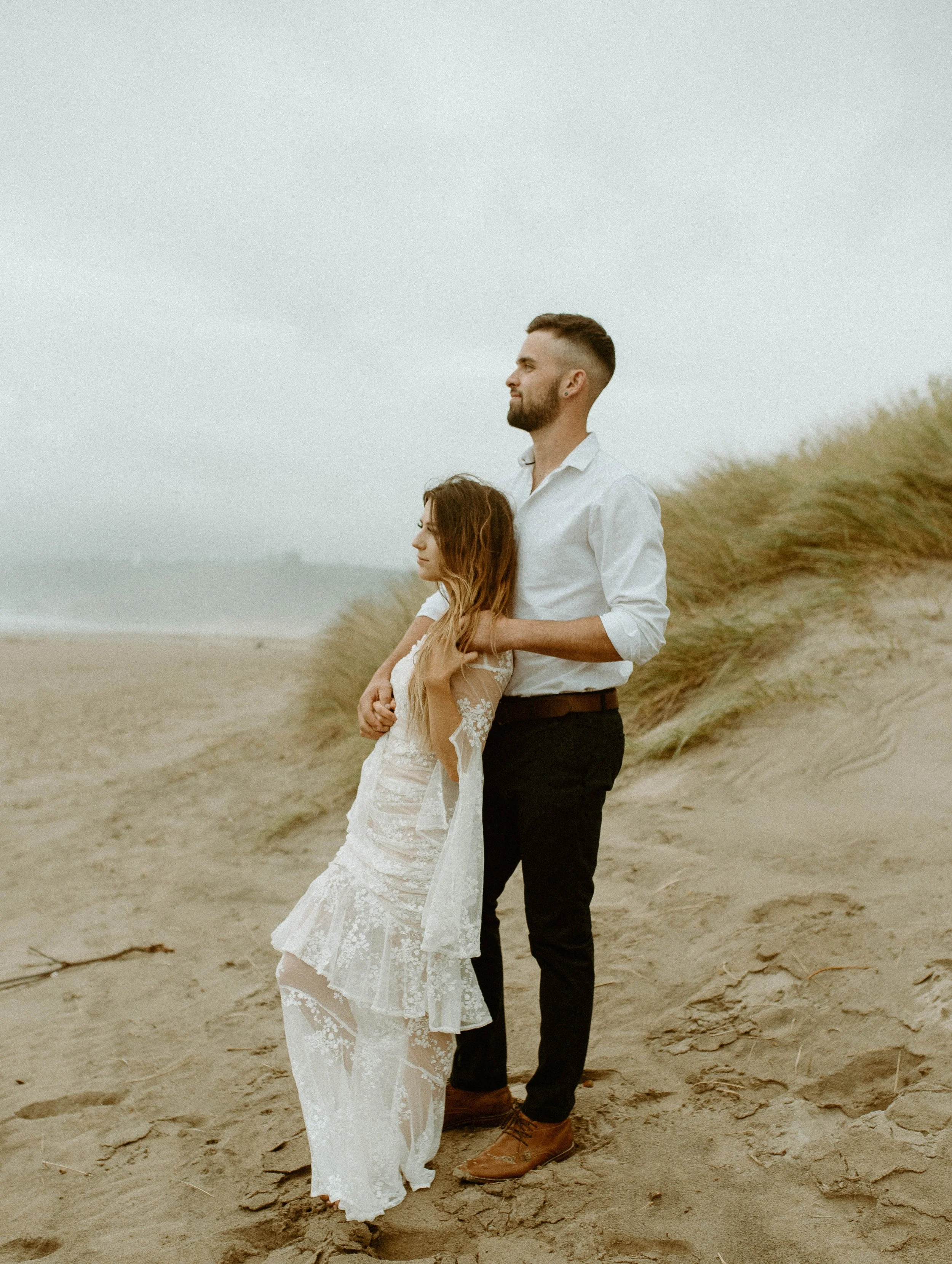 Bride and groom standing in the sand dunes on Cannon Beach Oregon during a foggy beach elopement session