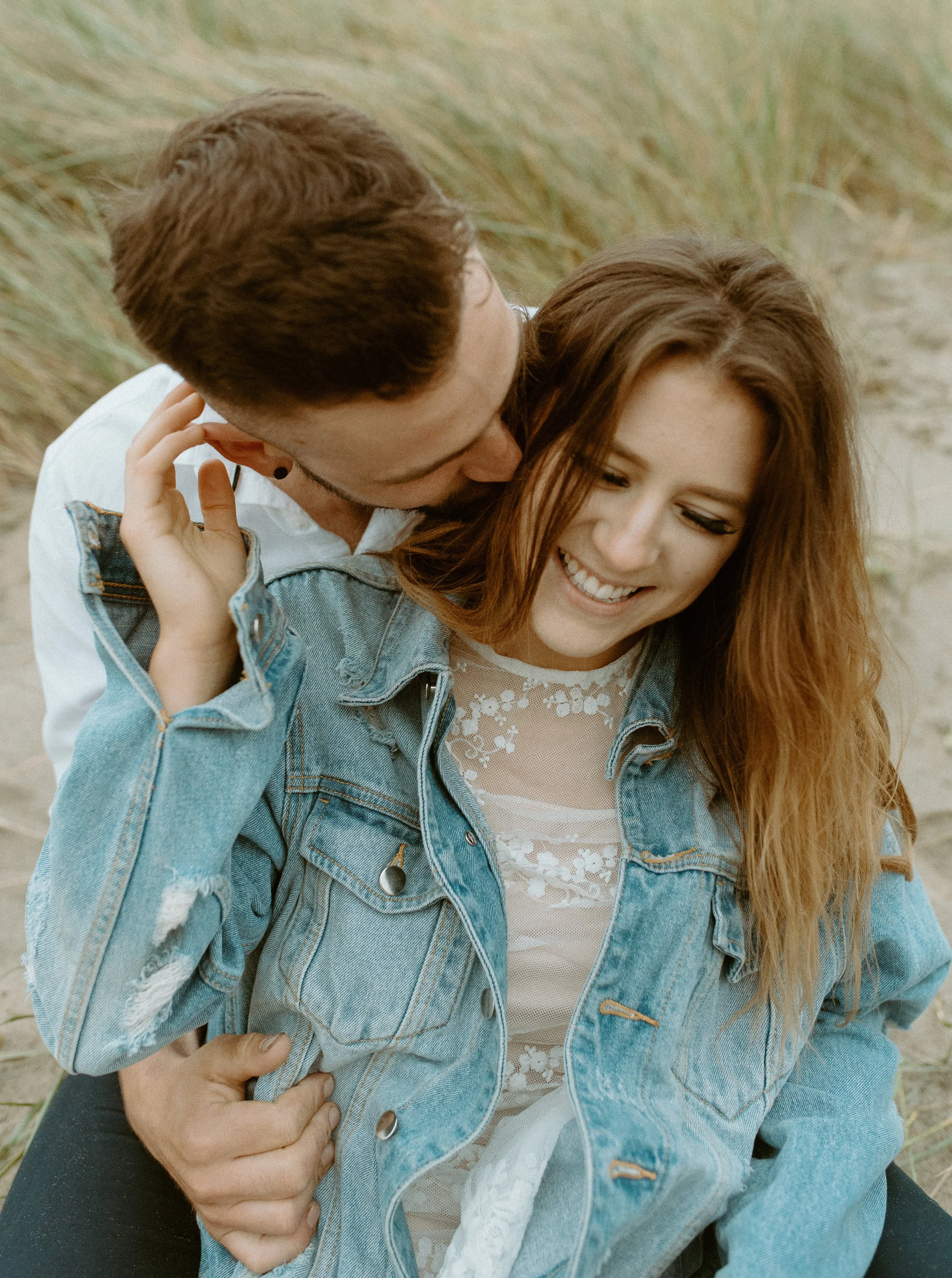 Joyful candid photo of bride and groom laughing together in the dunes at Cannon Beach Oregon during a coastal elopement session