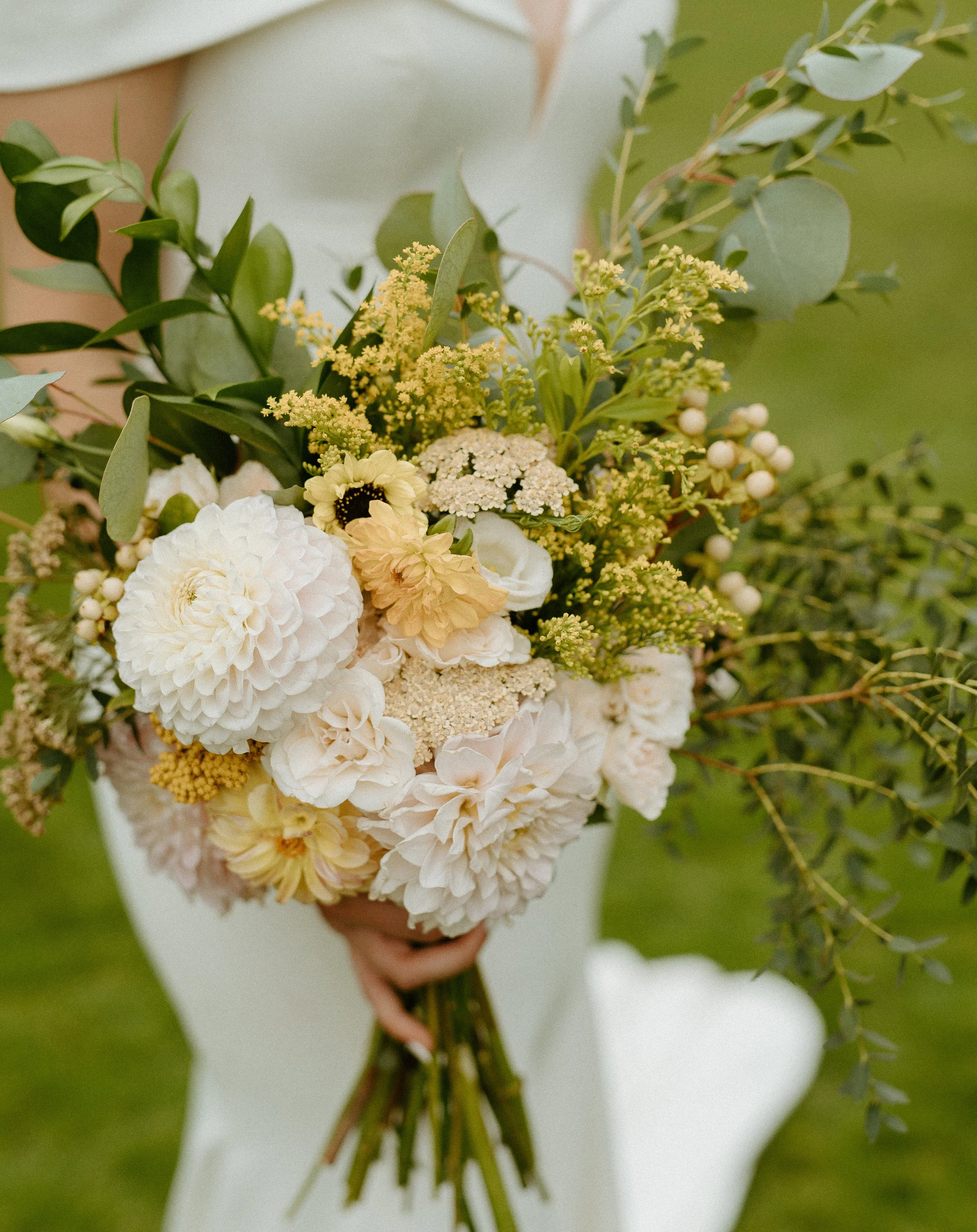 Bride holding bouquet of white and yellow flowers with greenery + outdoor wedding details + Washington wedding + Seattle wedding photographer