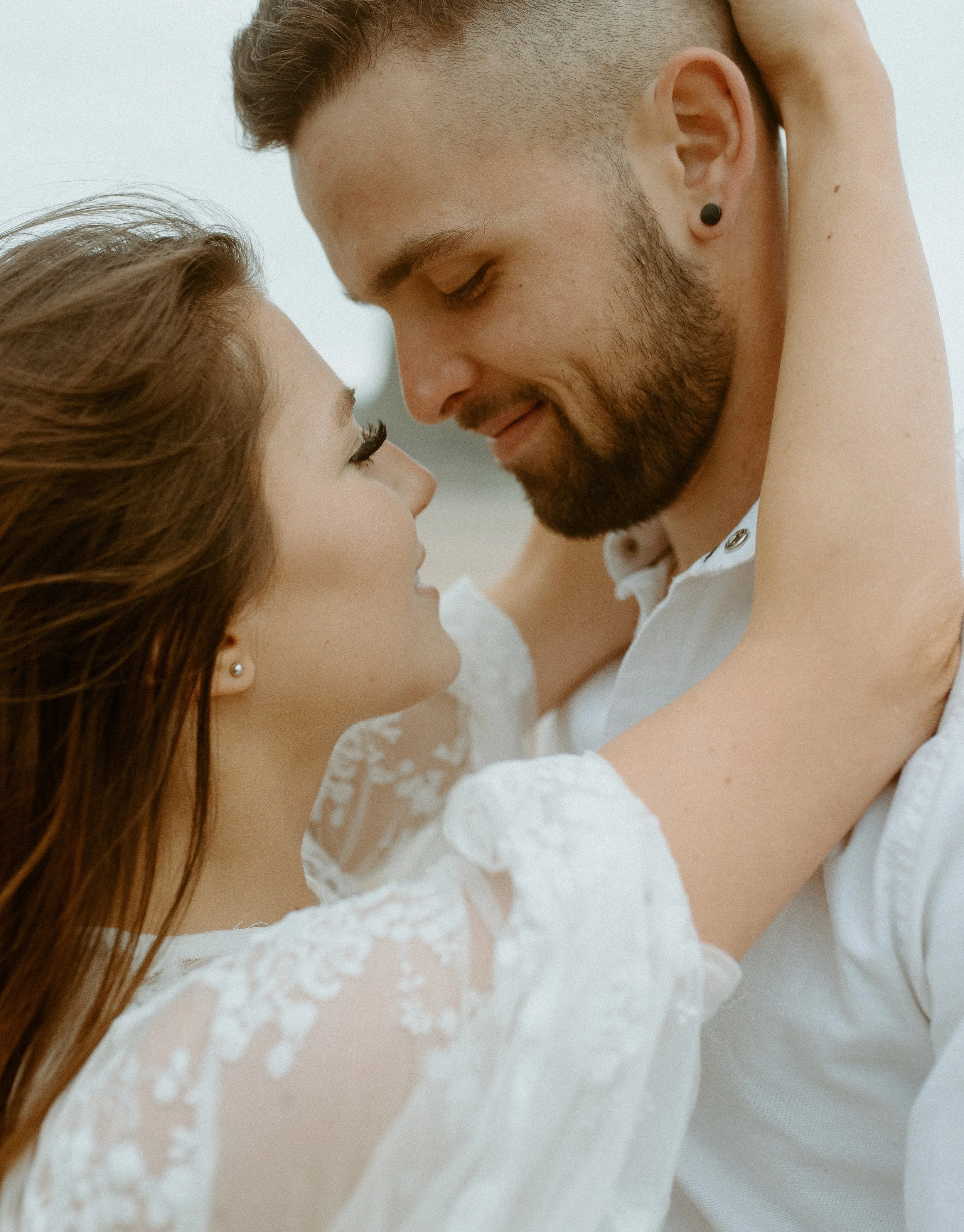 Intimate close up of bride and groom embracing on Cannon Beach Oregon with soft coastal light and romantic wedding styling