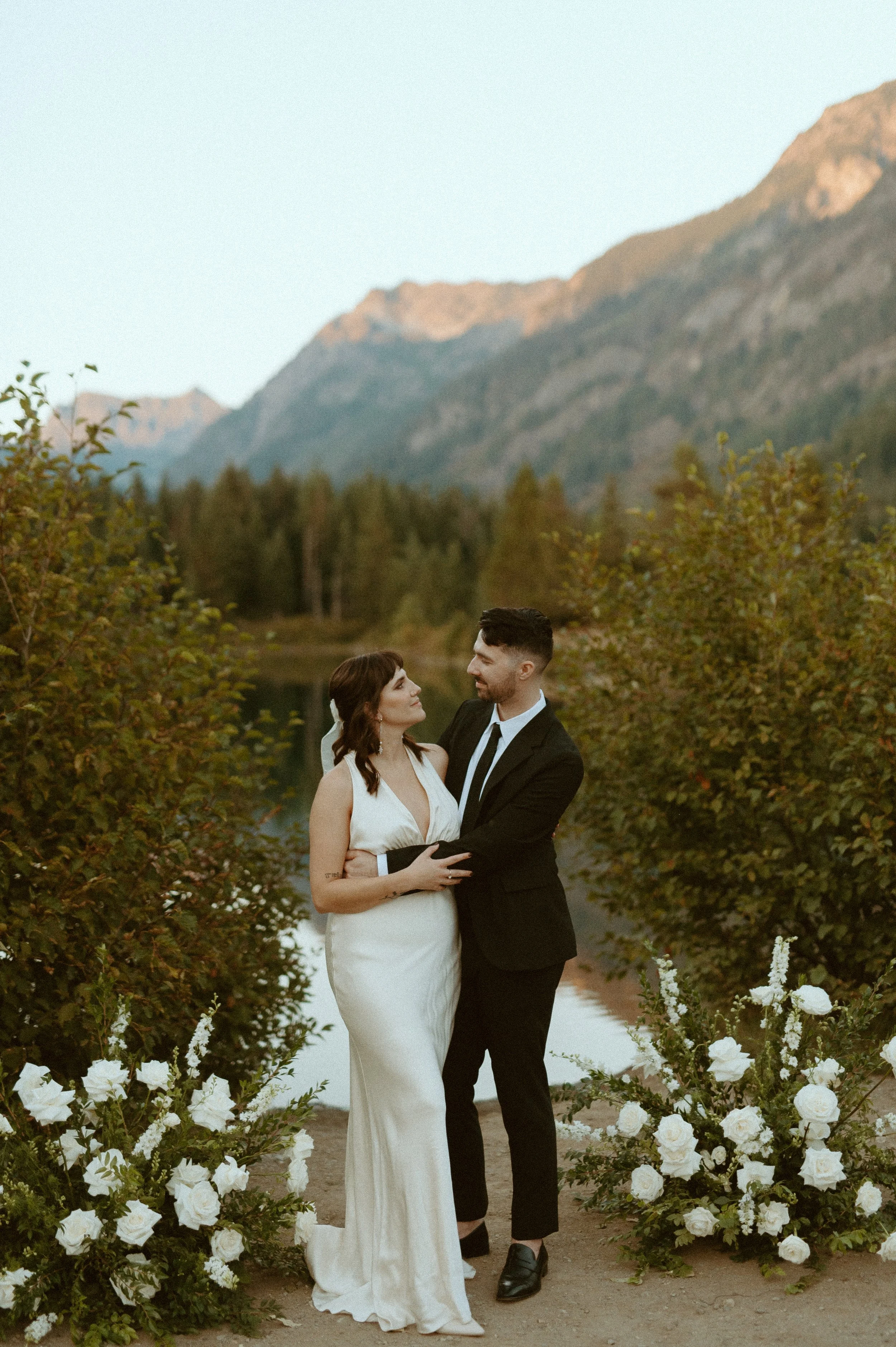 couple standing at Gold Creek Pond with mountain views + Washington elopement photographer + romantic PNW lakeside wedding