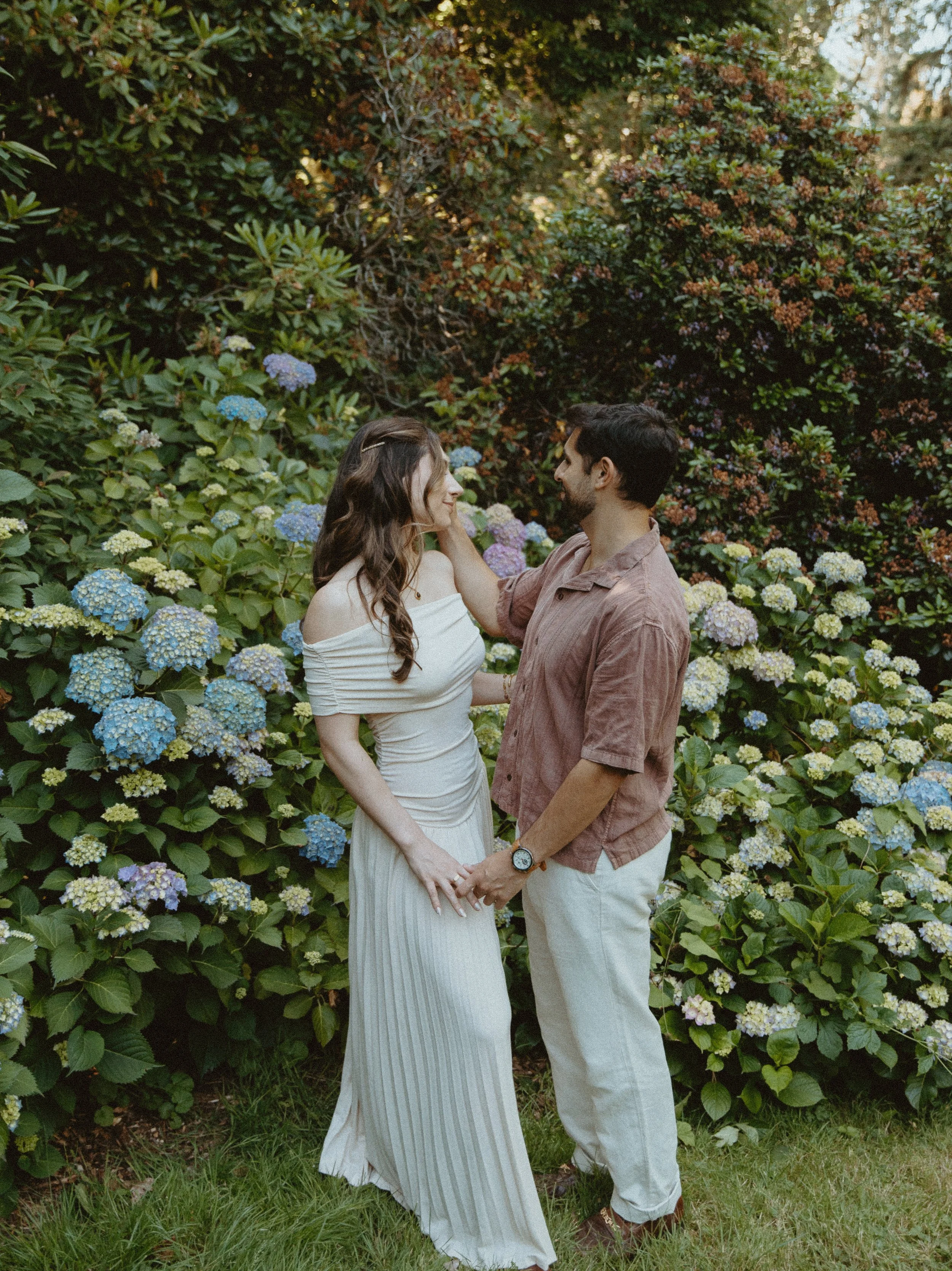 Couple standing close together surrounded by greenery + romantic interaction + Washington Park Arboretum engagement session + Seattle photographer