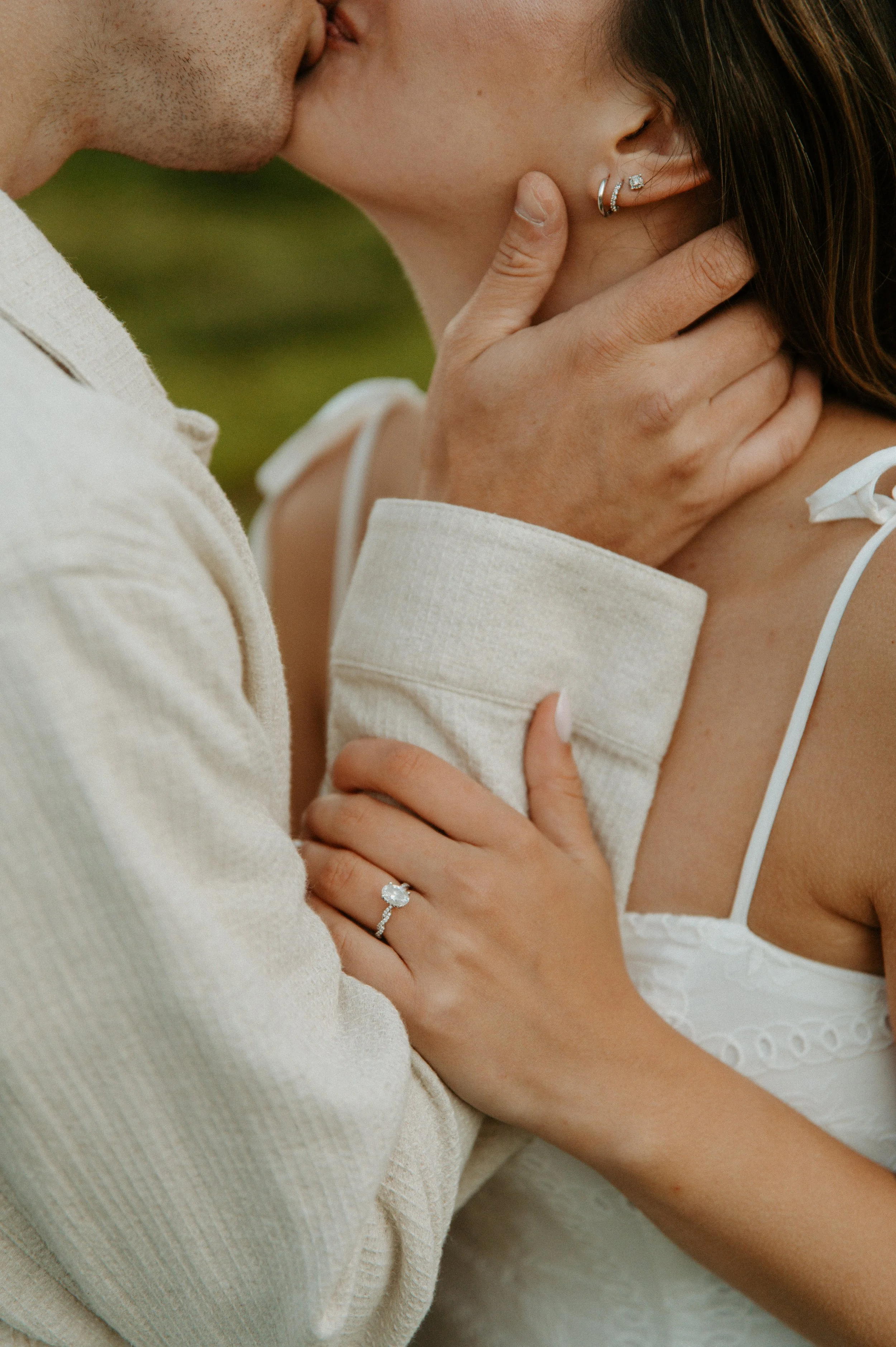 Close-up of an engagement ring on the bride-to-be’s hand surrounded by summer wildflowers
