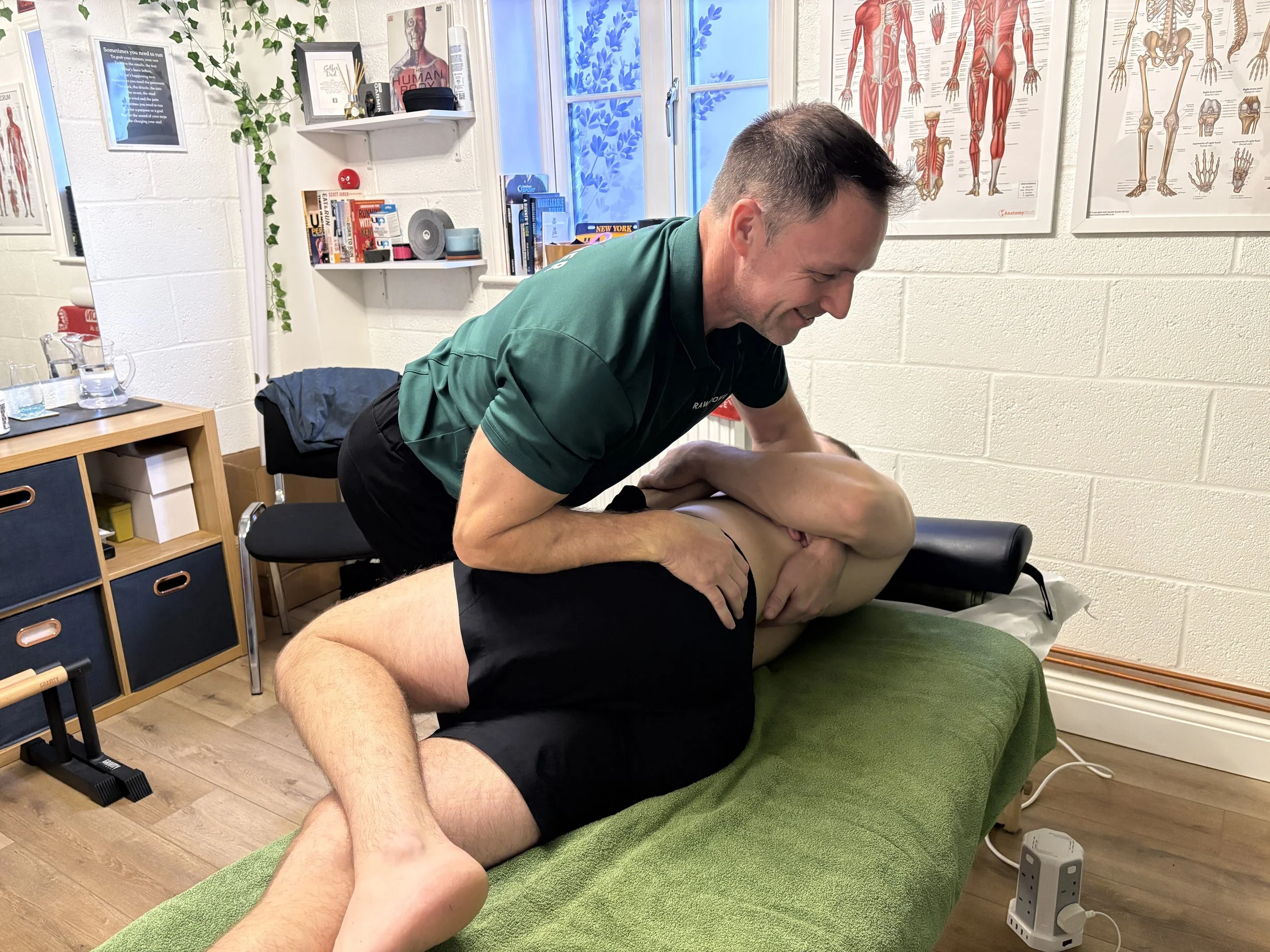 A chiropractor adjusting a patient's neck while lying on a chiropractic table in a treatment room.