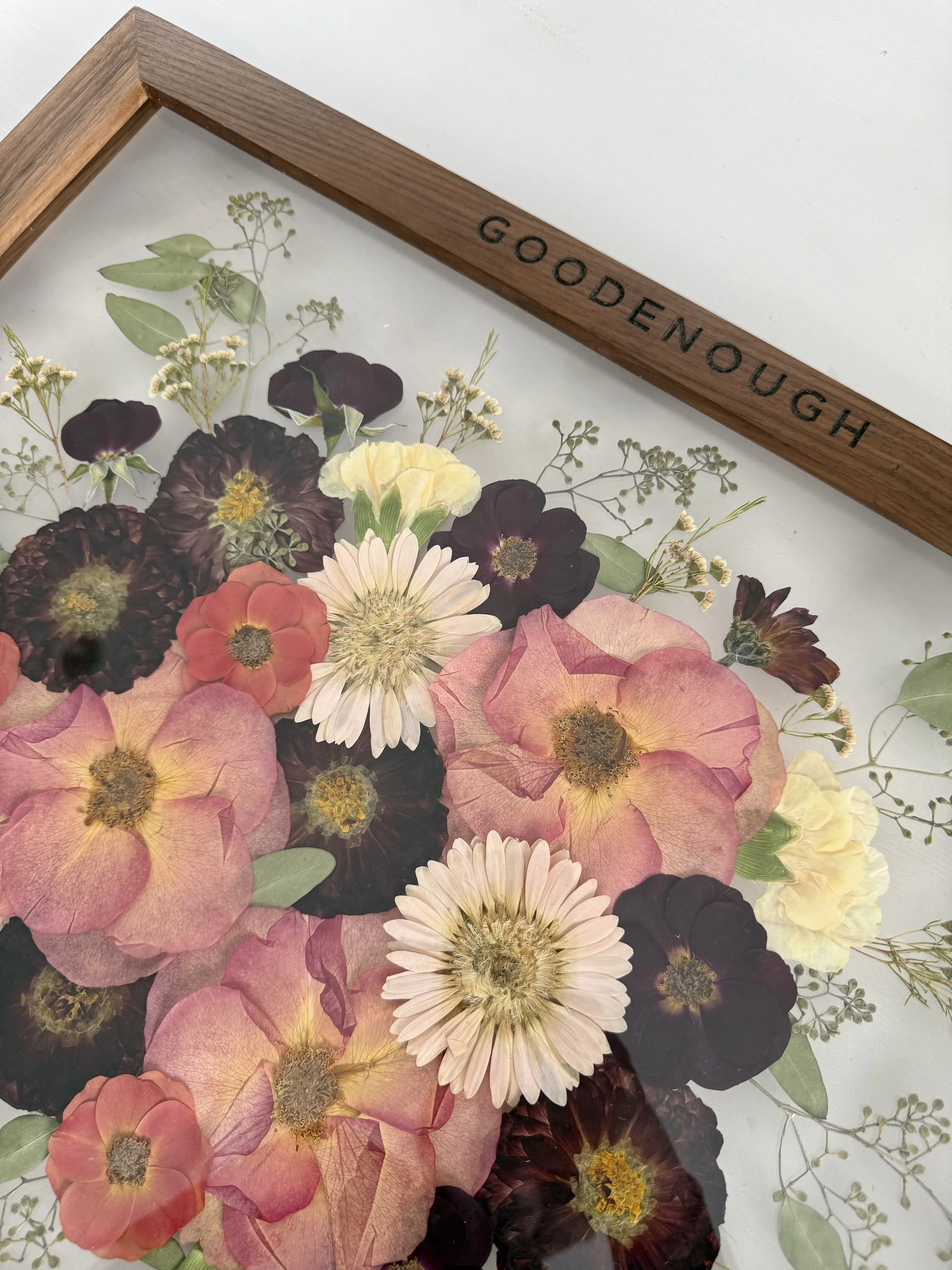 Pressed flowers preserved with last name engraved on the frame.