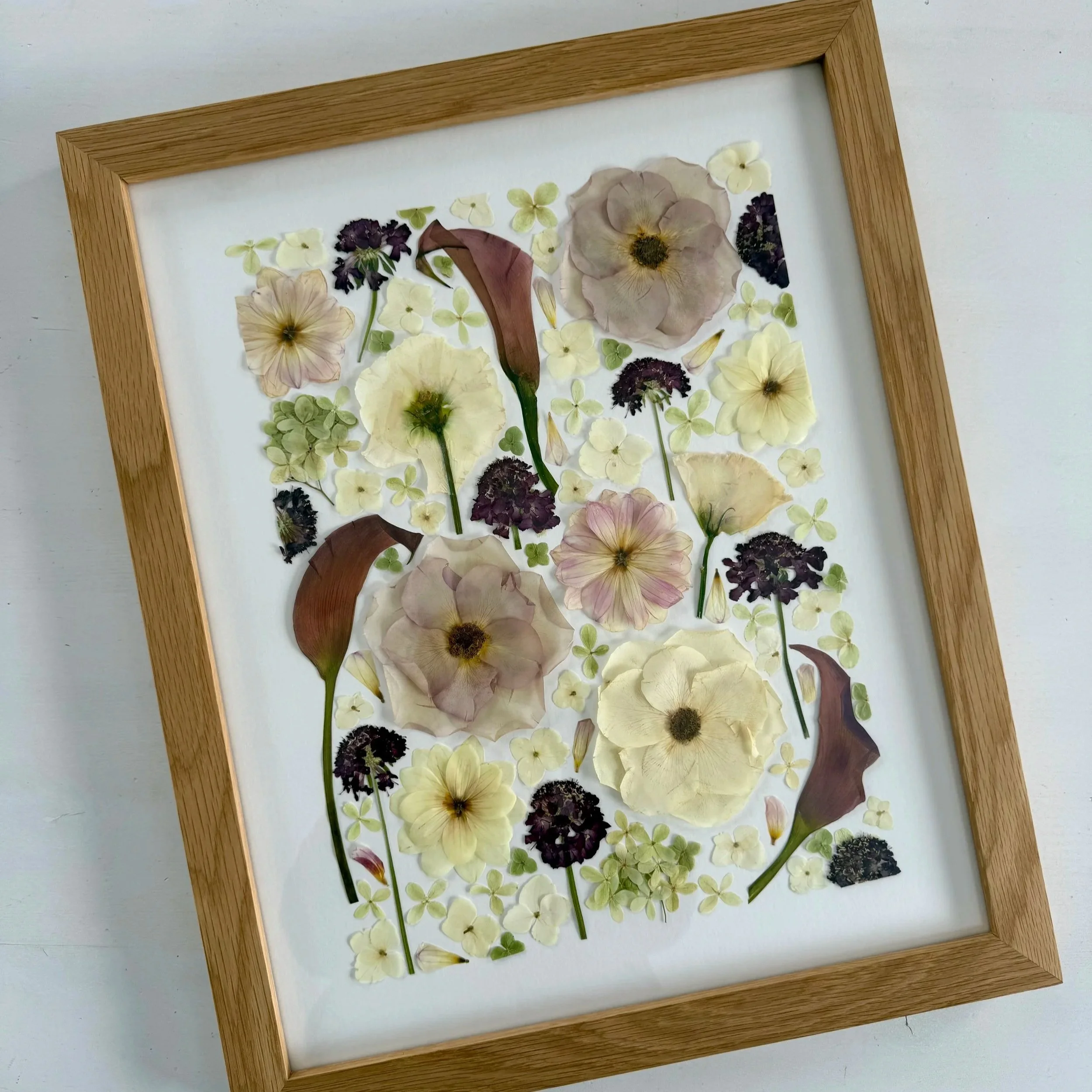 Botanical, deconstructed pressed flower design in a wood frame.
