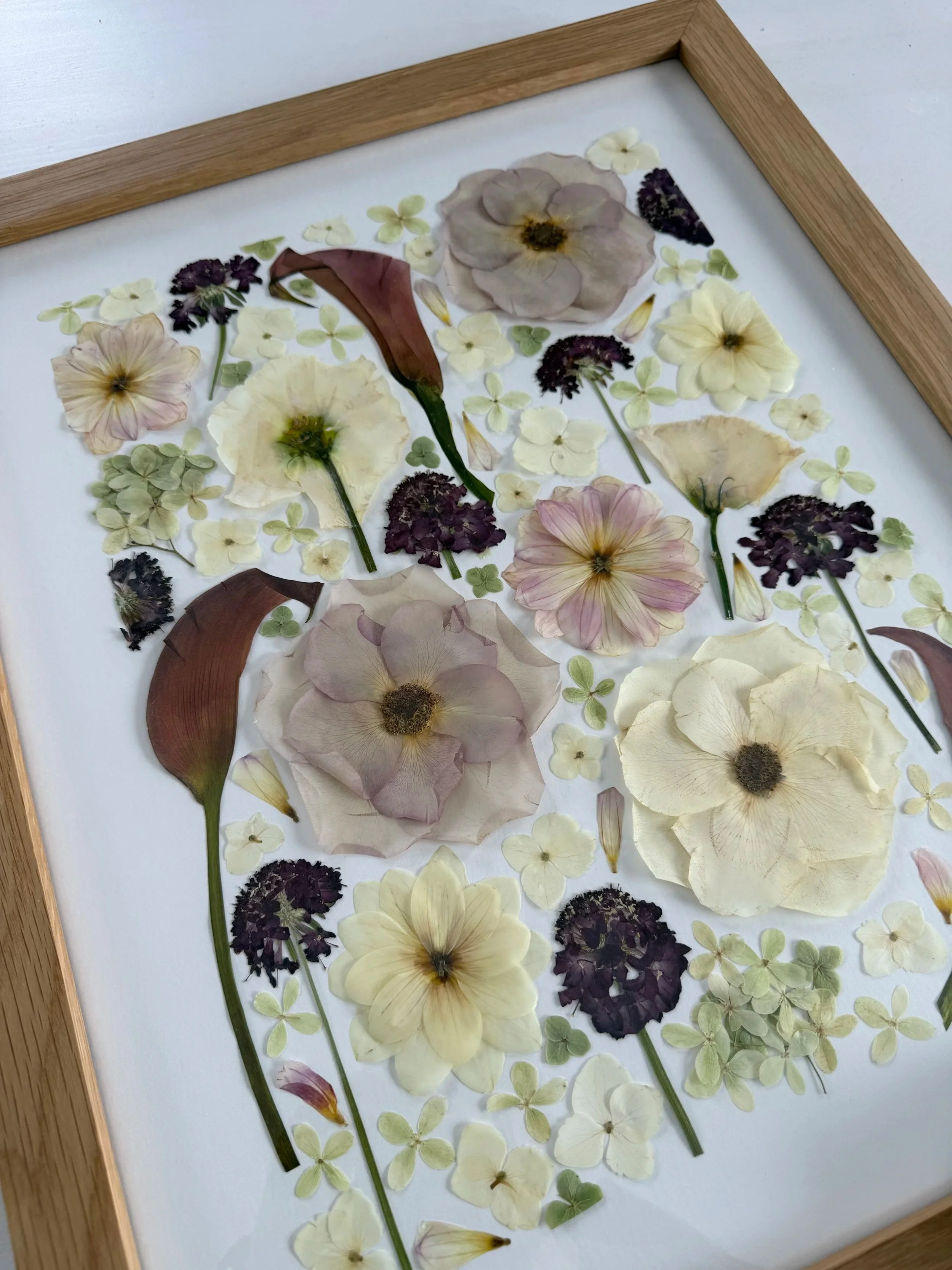 Botanical, deconstructed pressed flower design in a wood frame.
