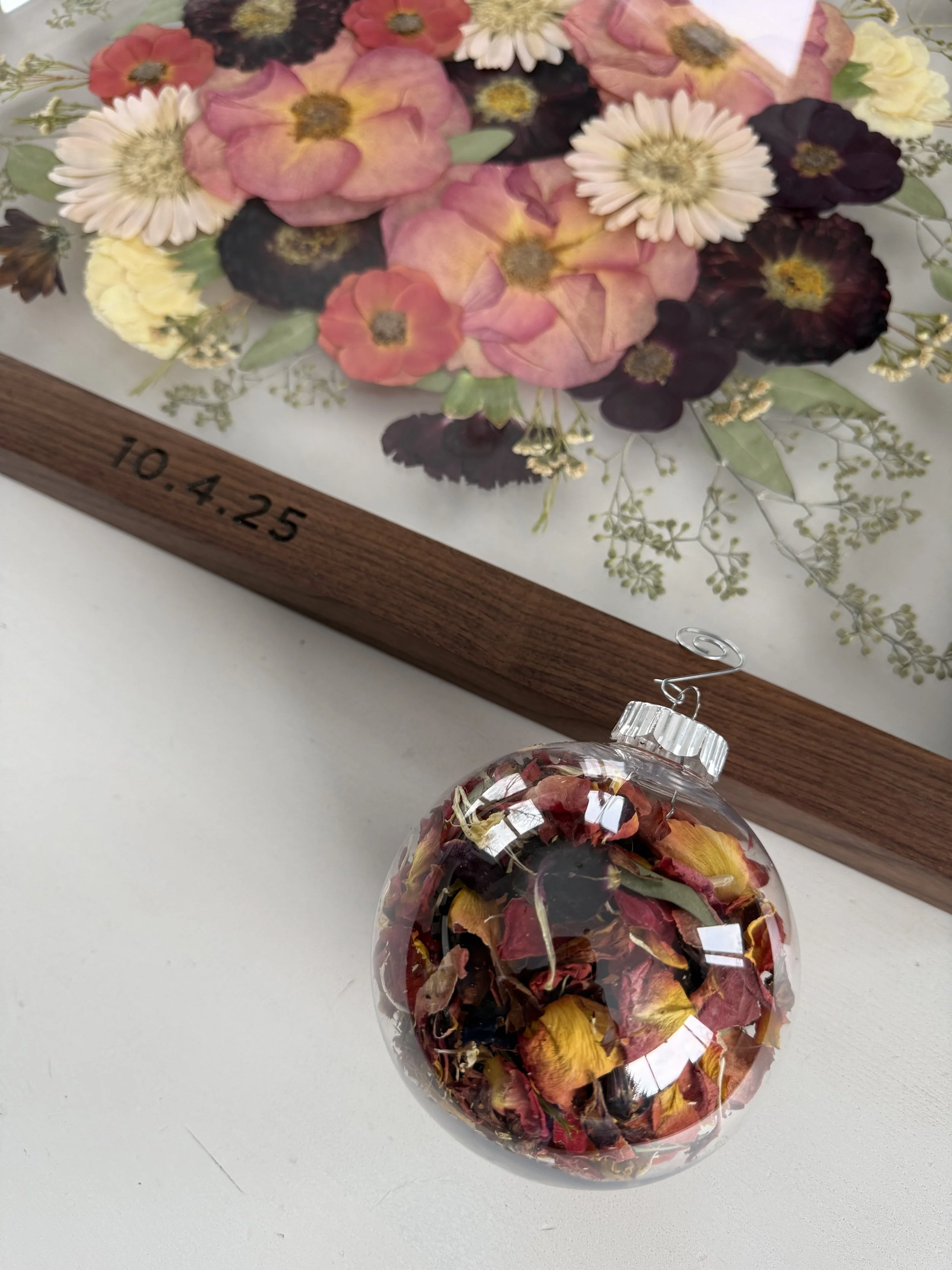 Pressed flowers in a frame with engraved date.
