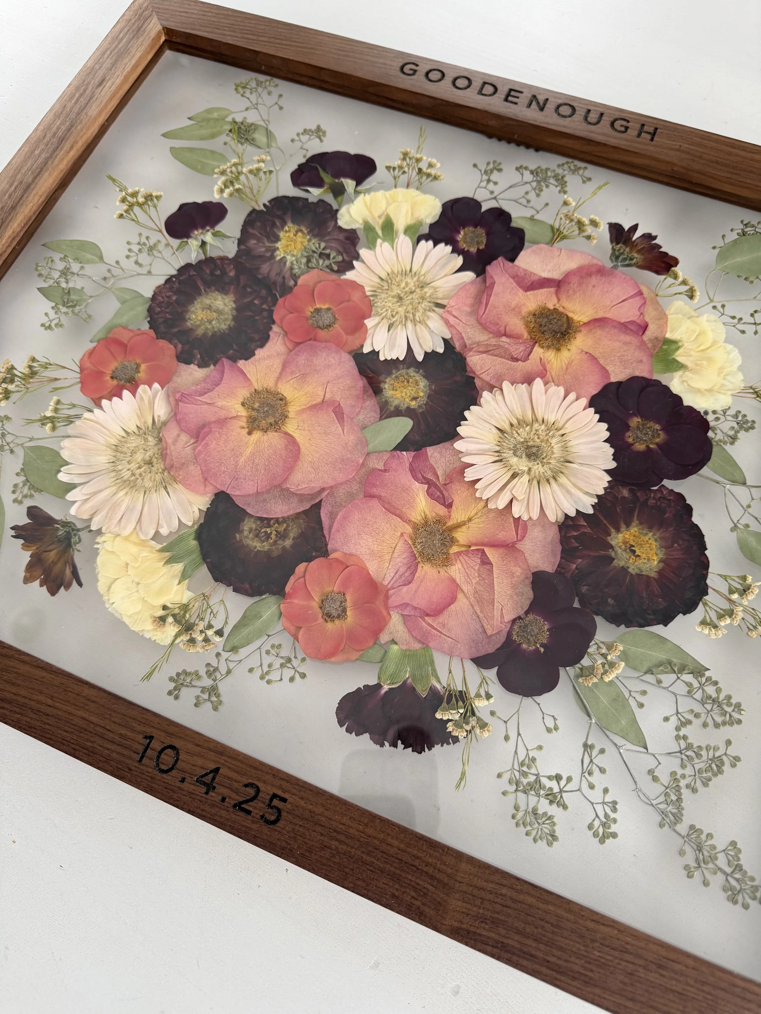 Pressed flowers preserved with last name engraved on the frame.