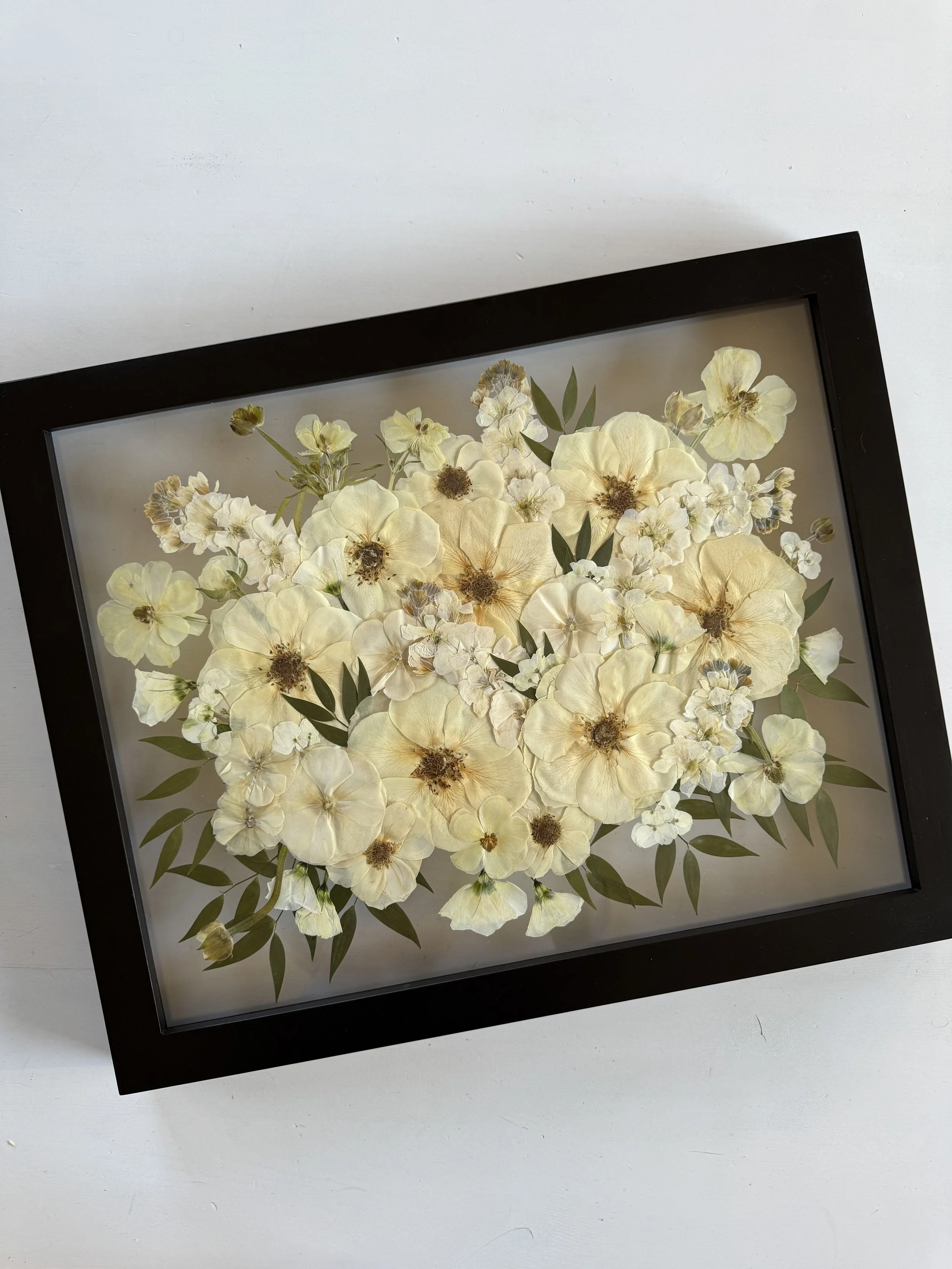 Framed and preserved white flower bridal bouquet in 16x20 inch size.