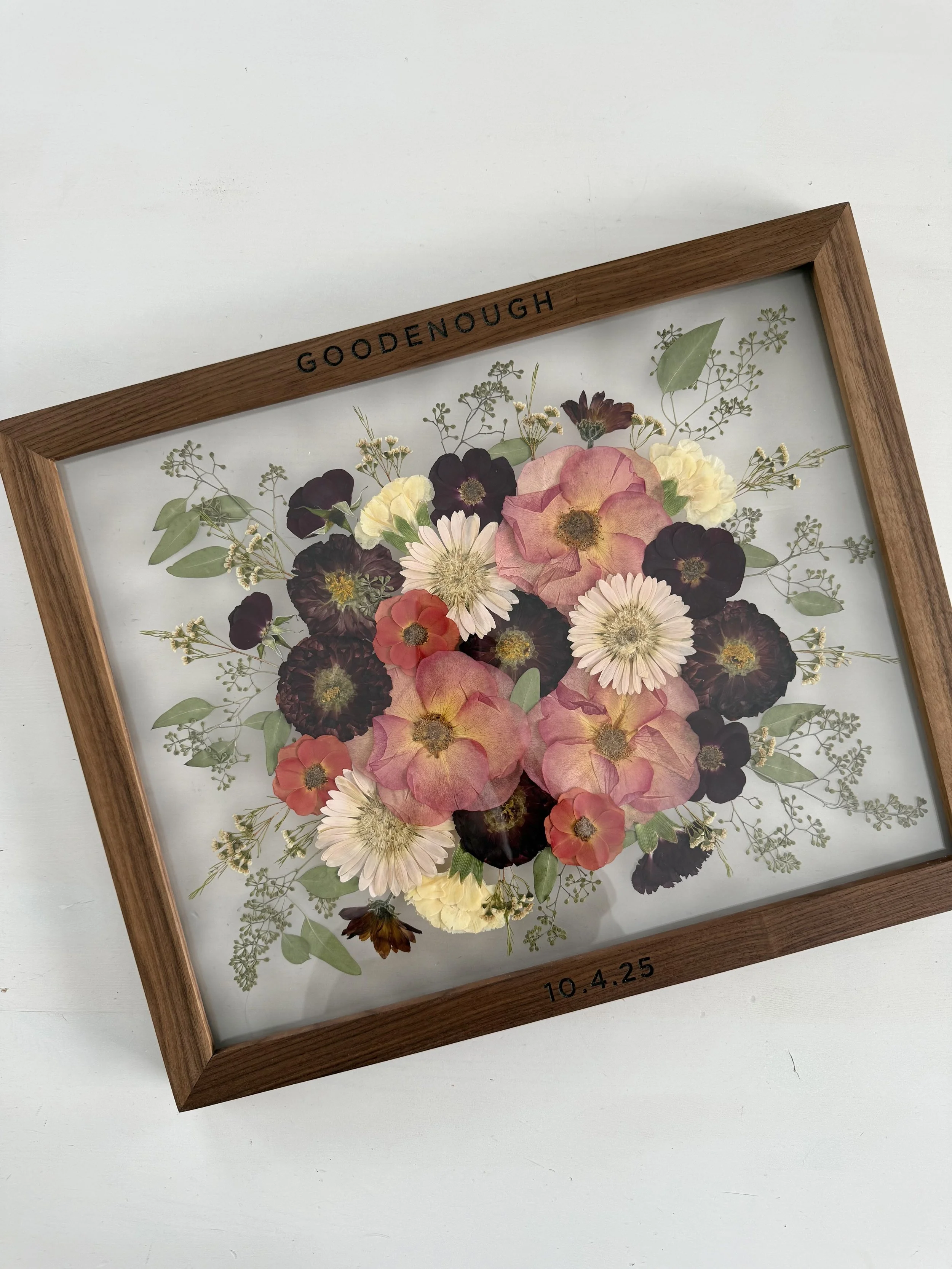 Pressed flowers preserved with last name engraved on the frame.
