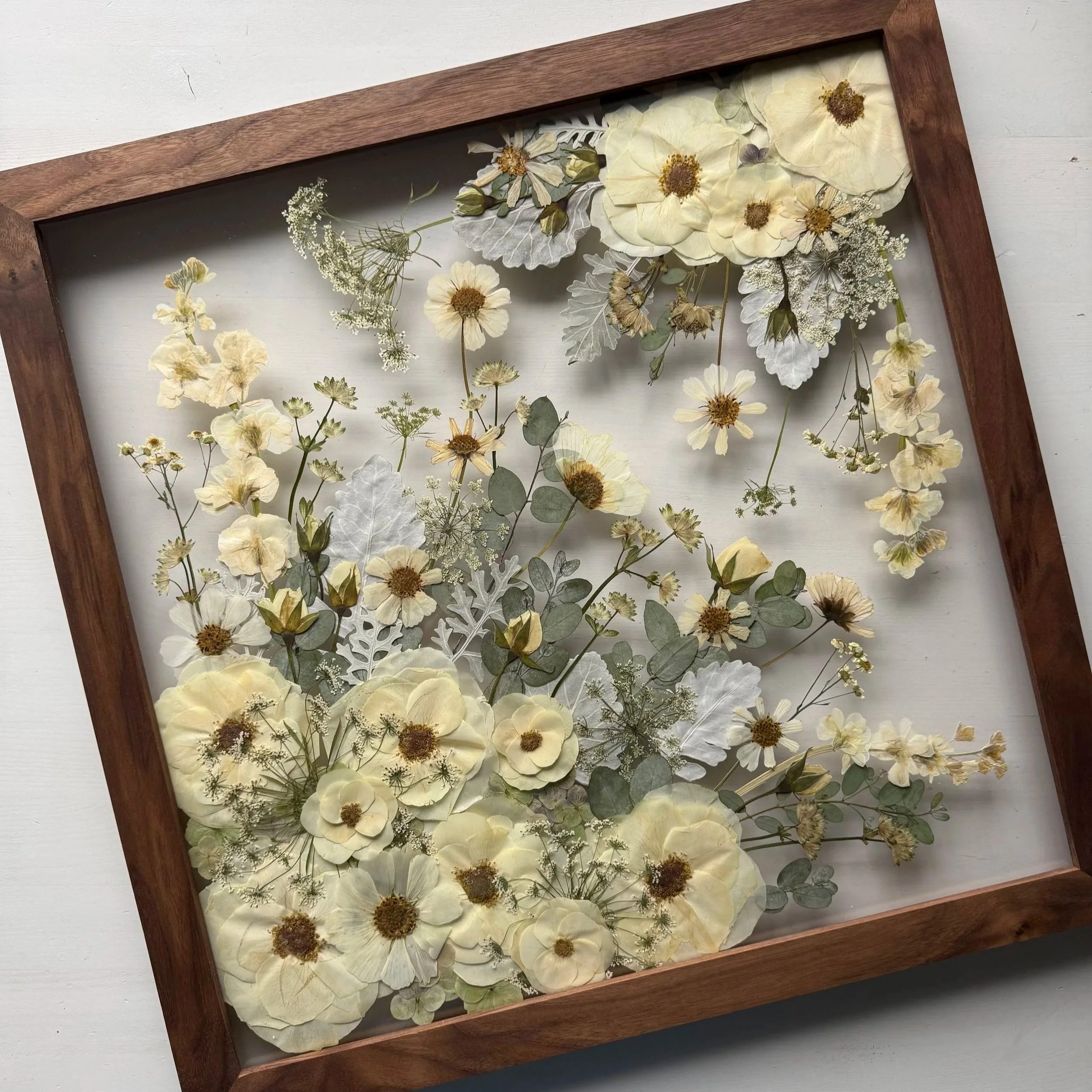Preserved and pressed wedding flowers in a walnut frame.