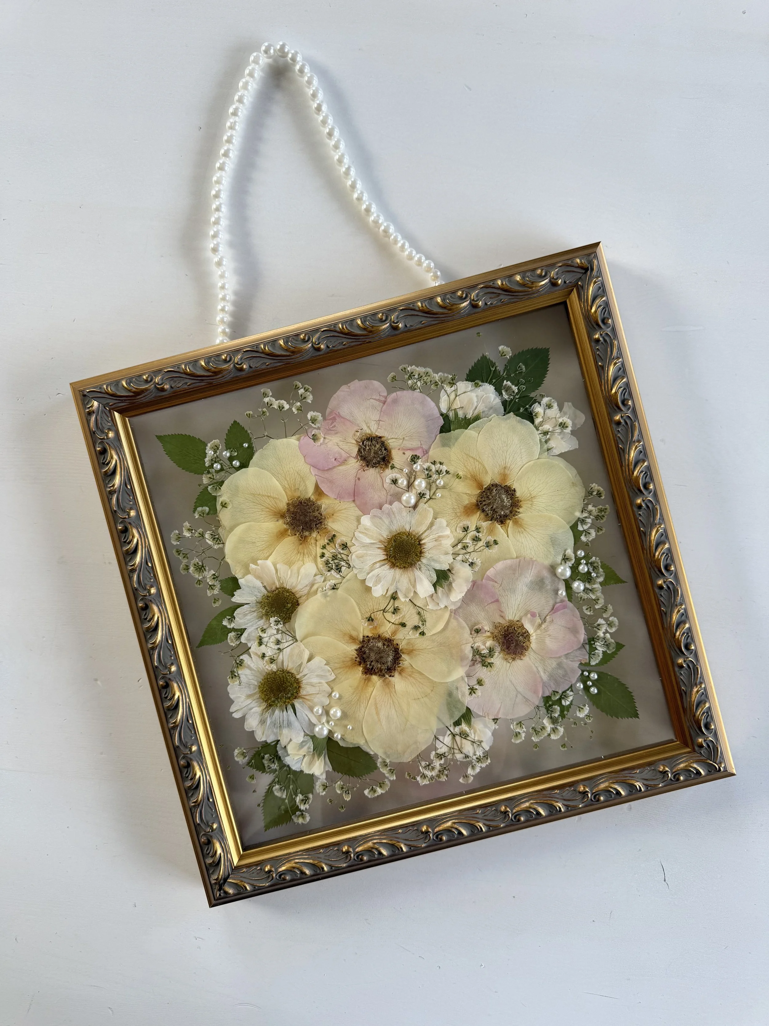 White and pink rose bridal bouquet flowers, pressed and framed in a bouquet design.