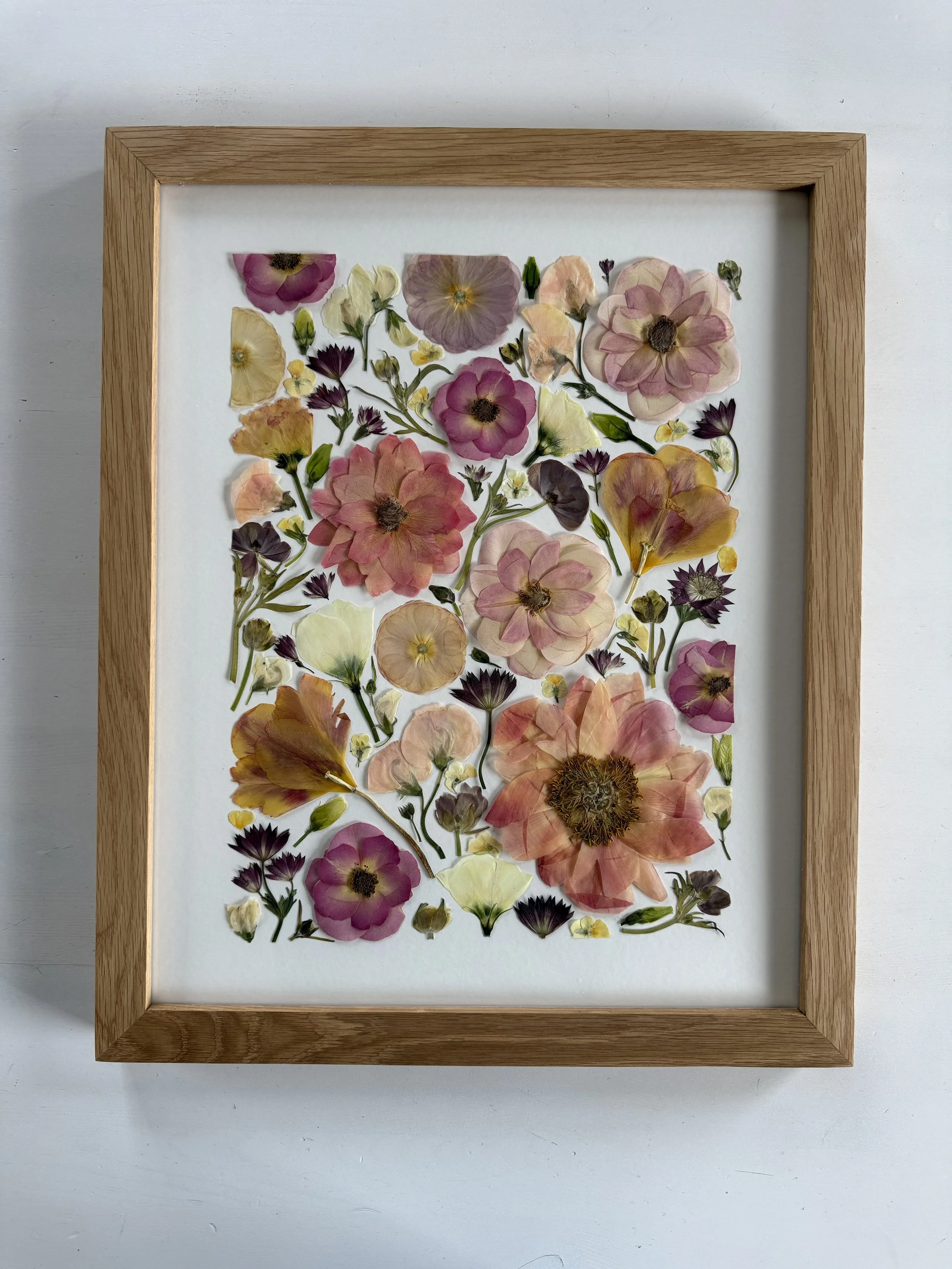 Deconstructed pressed flower design in a frame.
