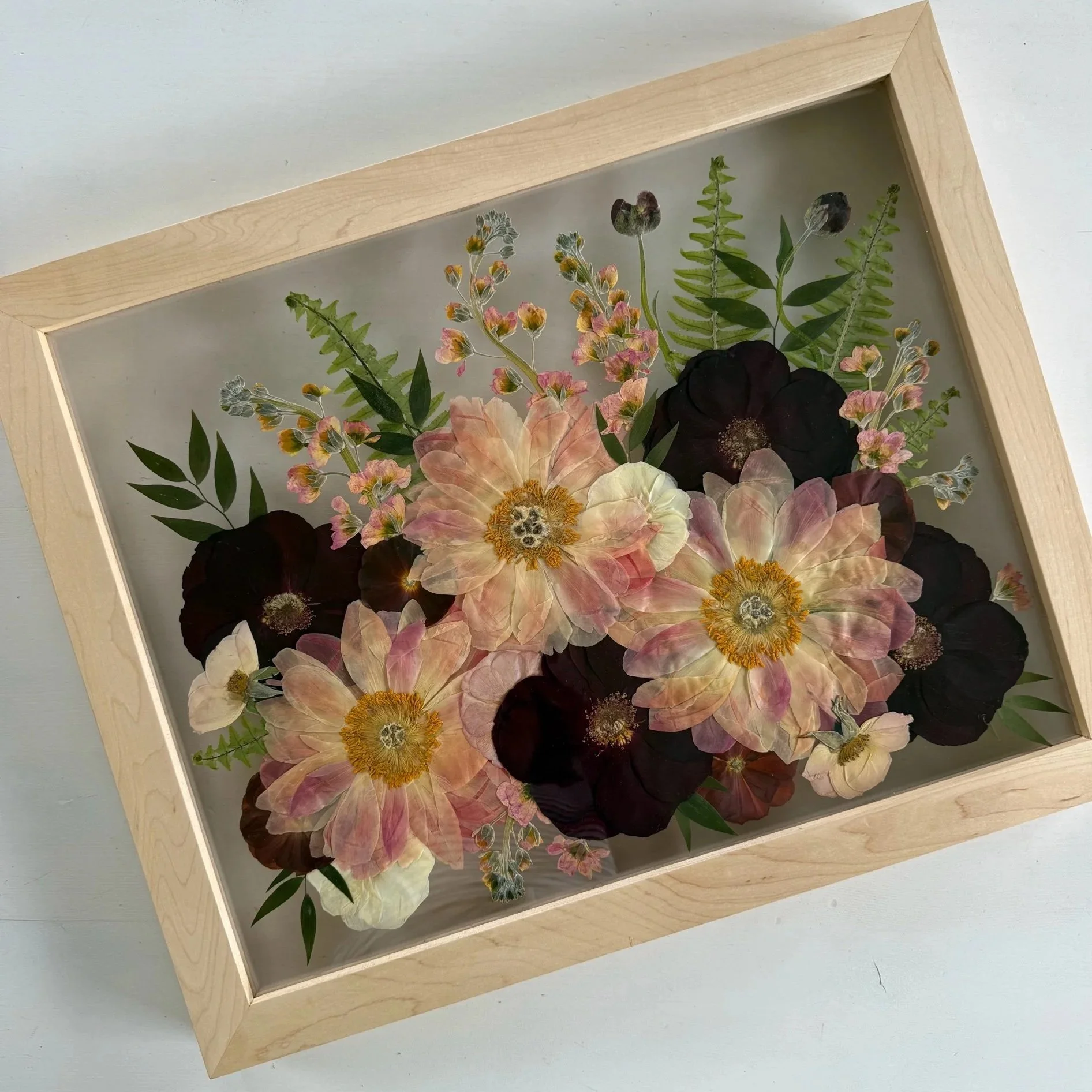 Pressed and framed pink peonies and red roses in maple frame.