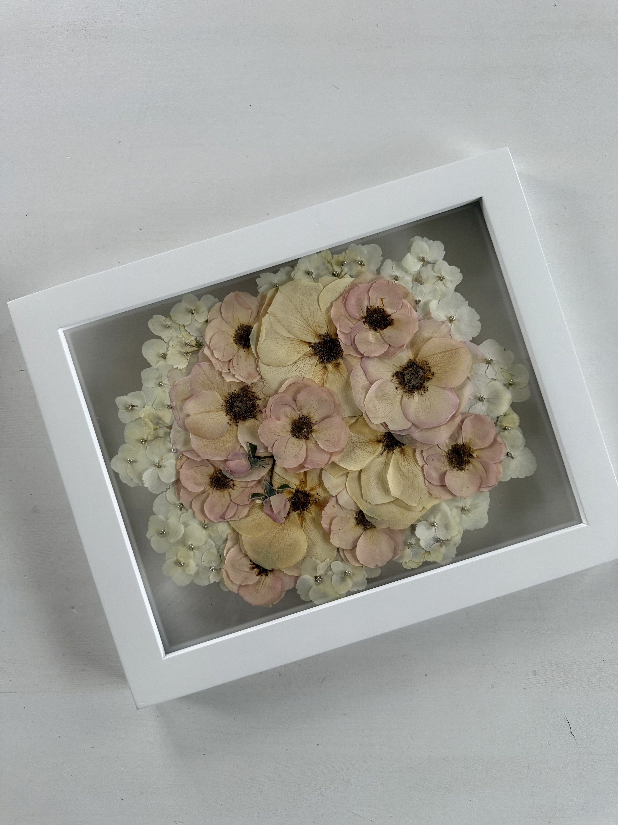 White and pink rose bridal bouquet flowers, pressed and framed in a bouquet design.