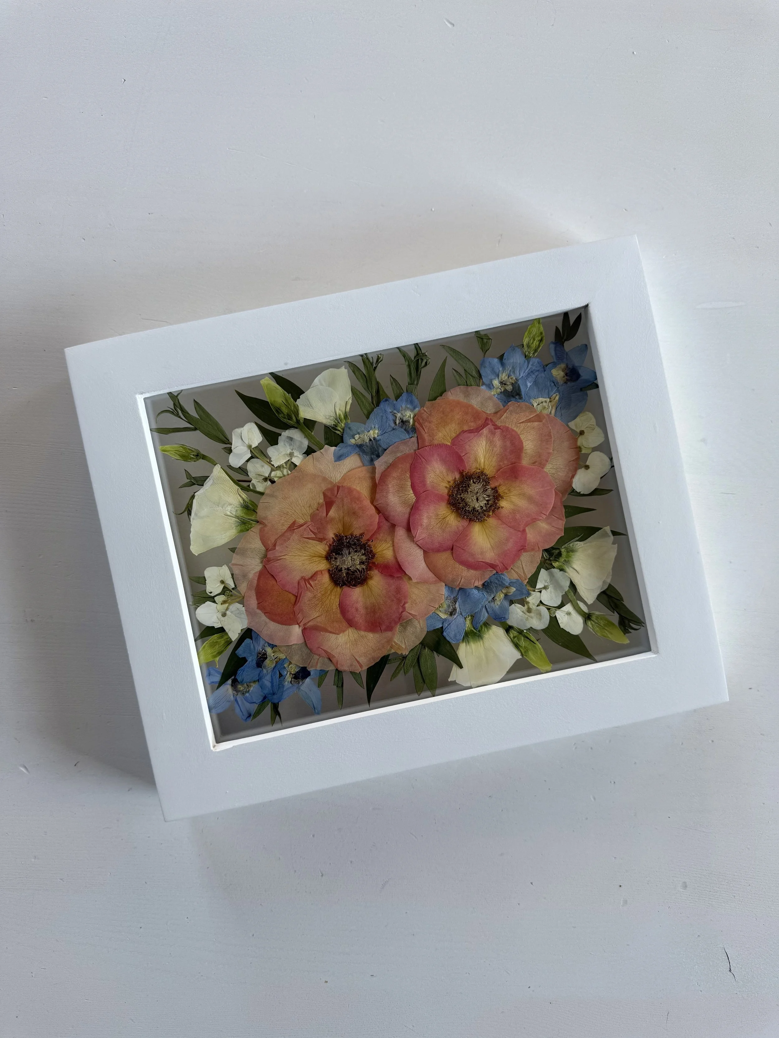 Orange rose and blue delphinium summer bridal bouquet flowers, pressed and framed in a bouquet design.