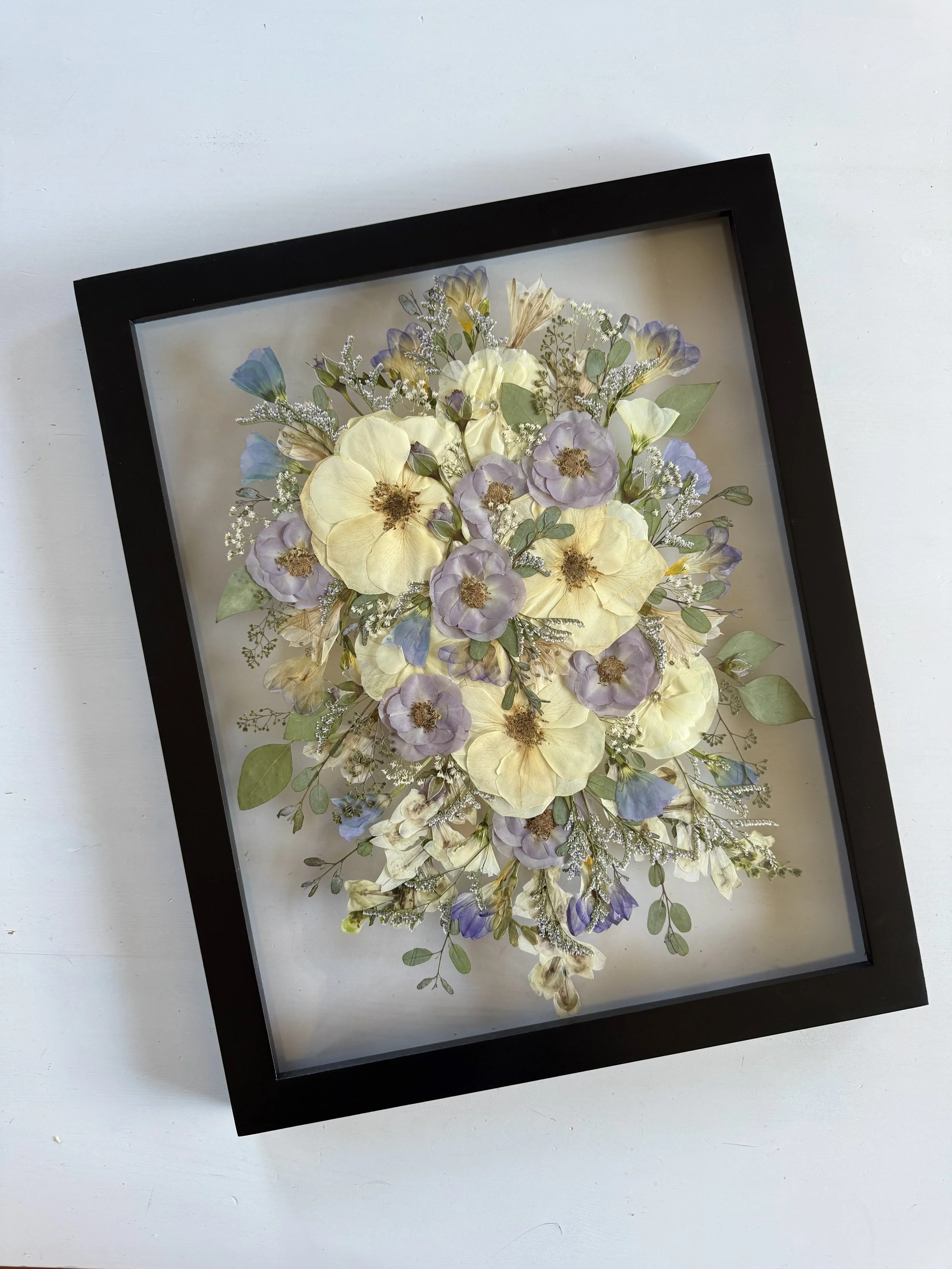 Framed and preserved lavendar and white bridal flowers in a bouquet design.