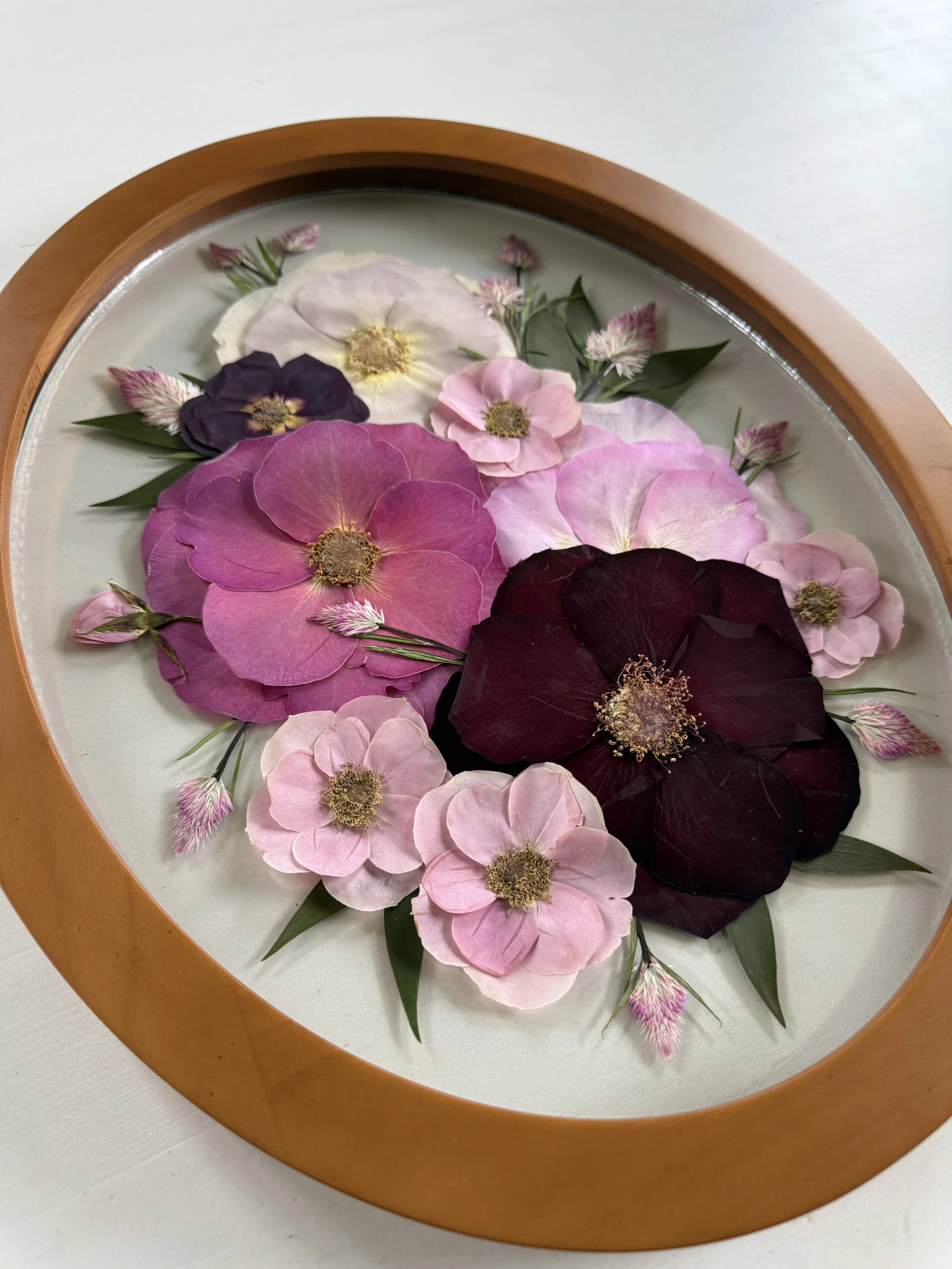 Pressed flowers framed in an oval frame. (Copy)