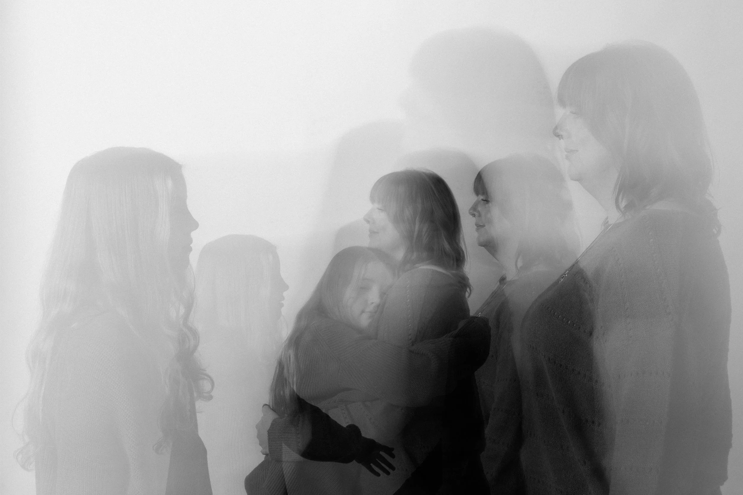 Multiple overlapping images of women, some smiling, embracing, and talking, in a grayscale, layered photograph.