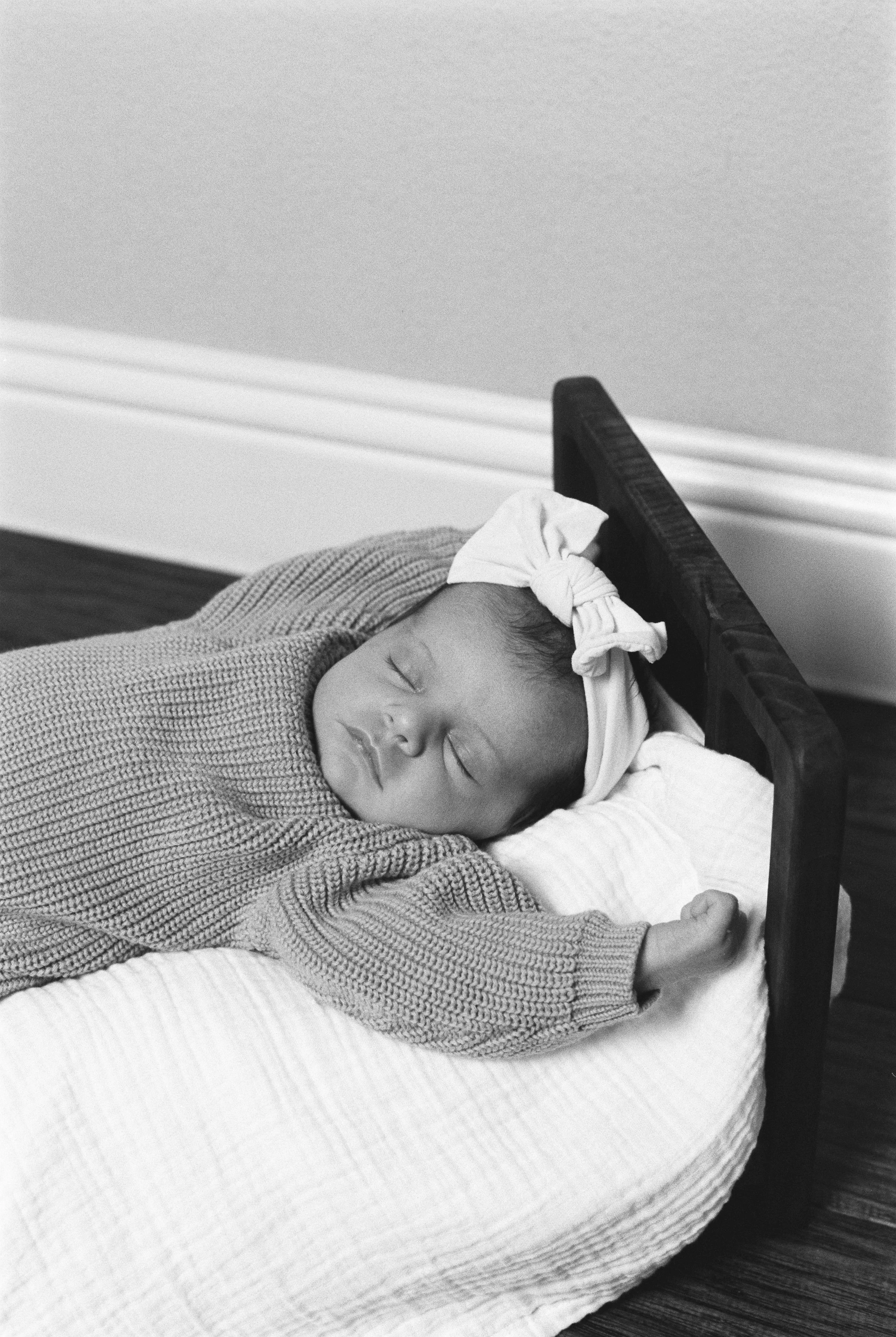 A young child with a headband sleeping on a small bed.
