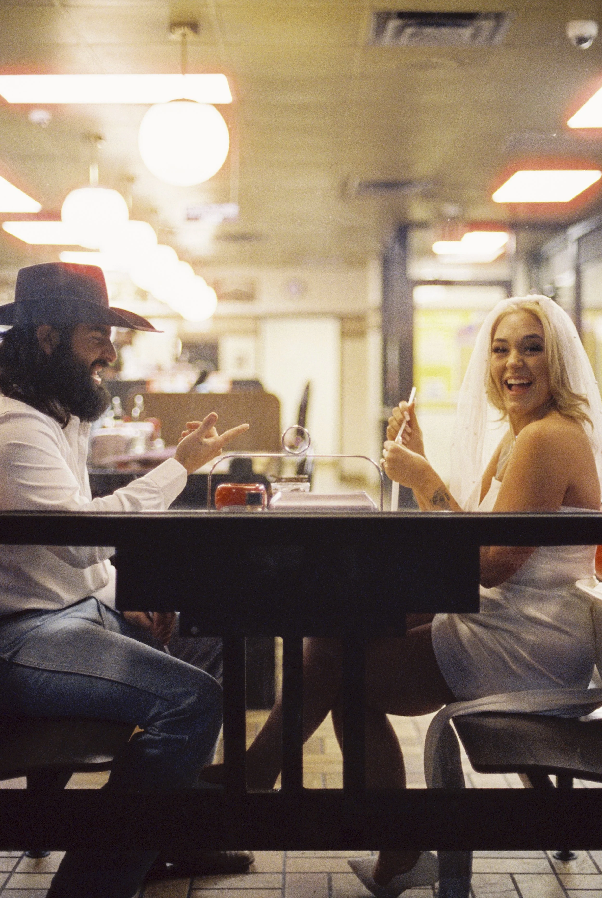 A man and a woman are sitting at a table in a restaurant, smiling and enjoying a conversation.