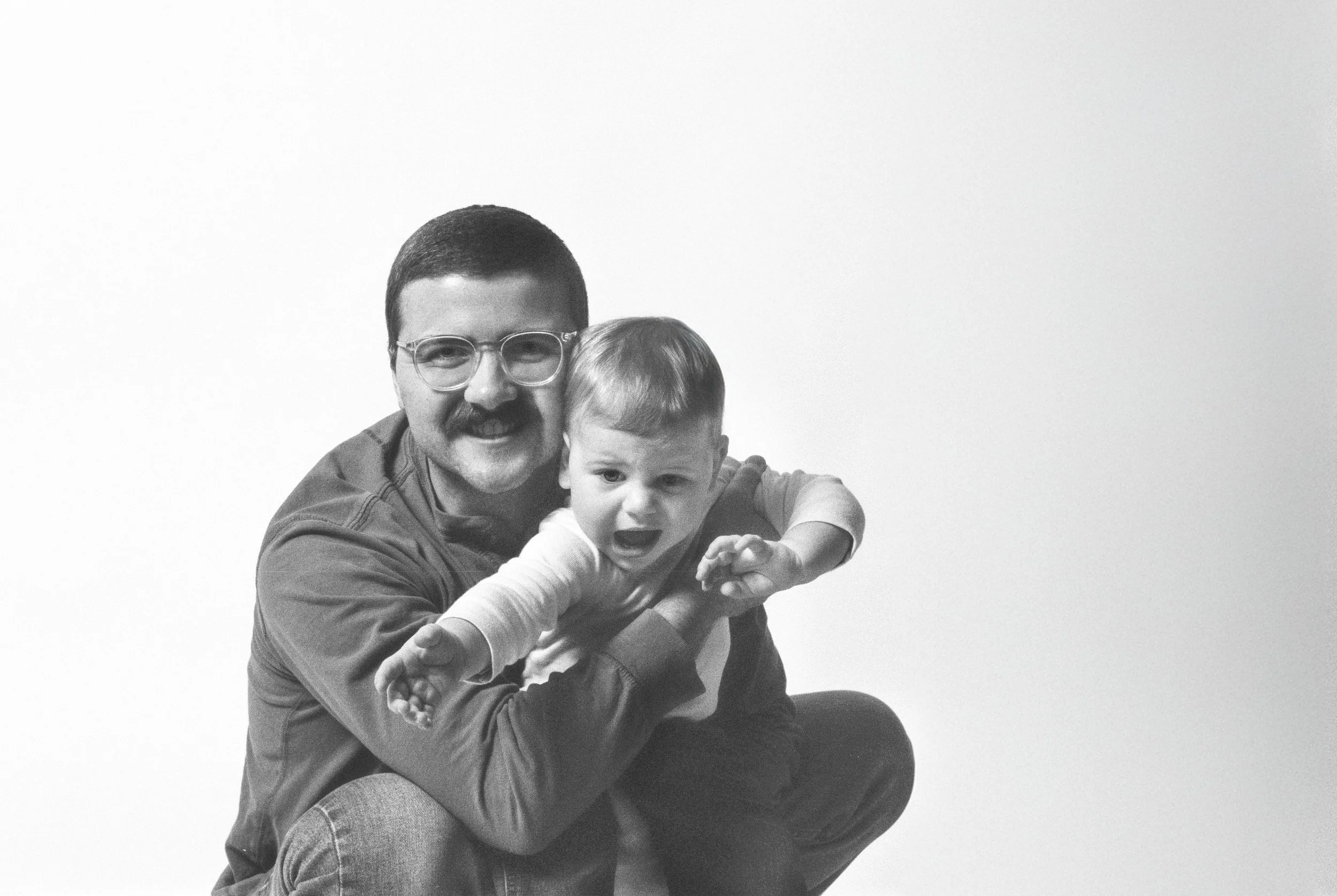 Black and white photo of a man with glasses and a mustache playing with a young child.
