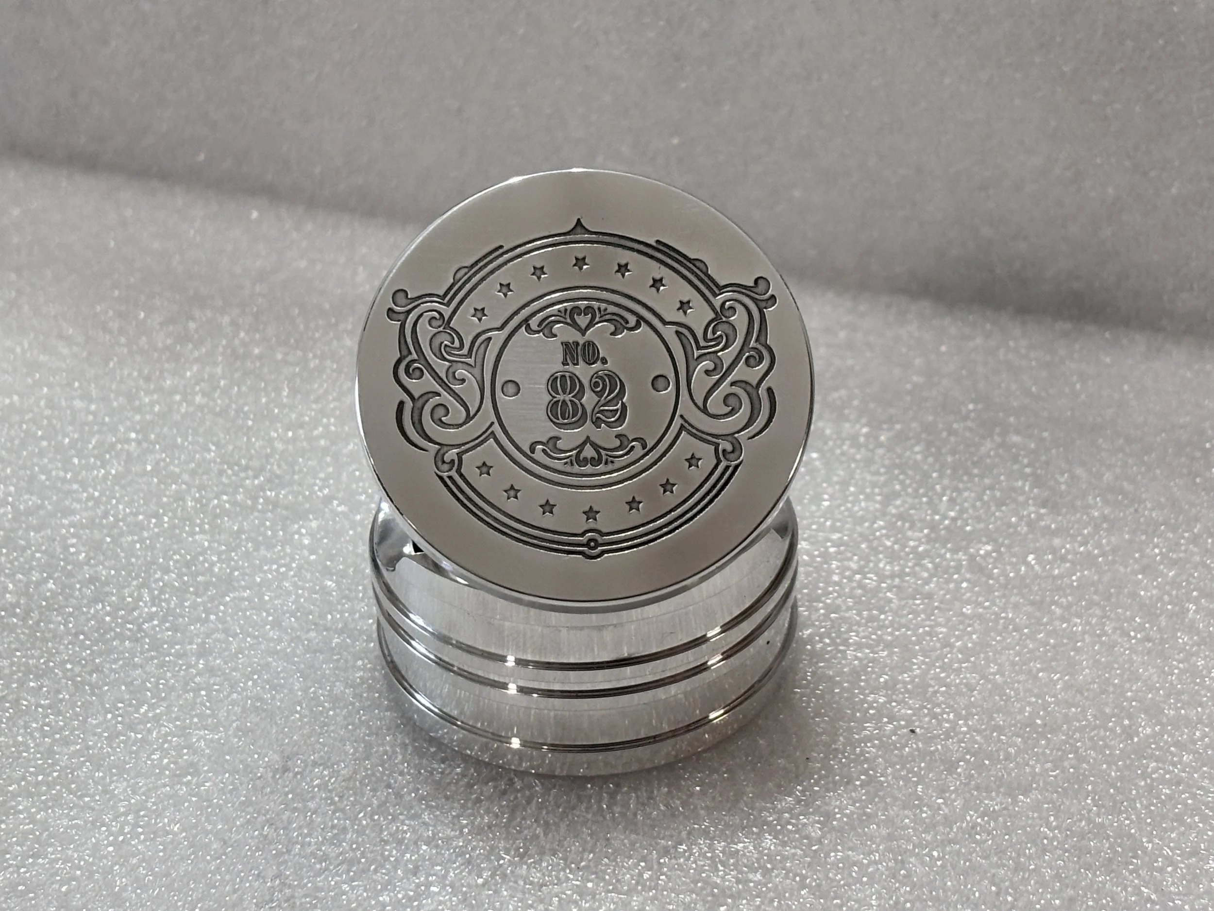 Stacked shiny silver coins with engraved design and the number 82 on top, placed on a sparkly white surface.
