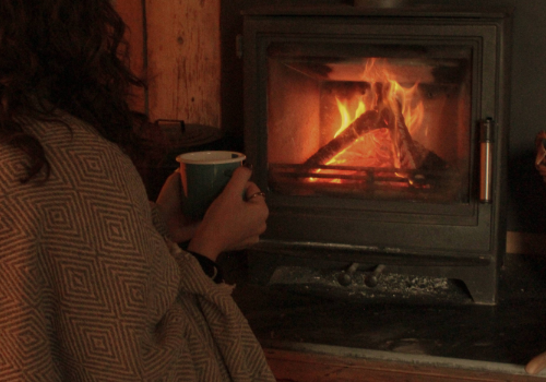 Girl by the fire with mug of tea