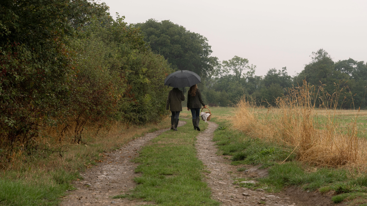 Two girls in country attire walking through the field at autumn time