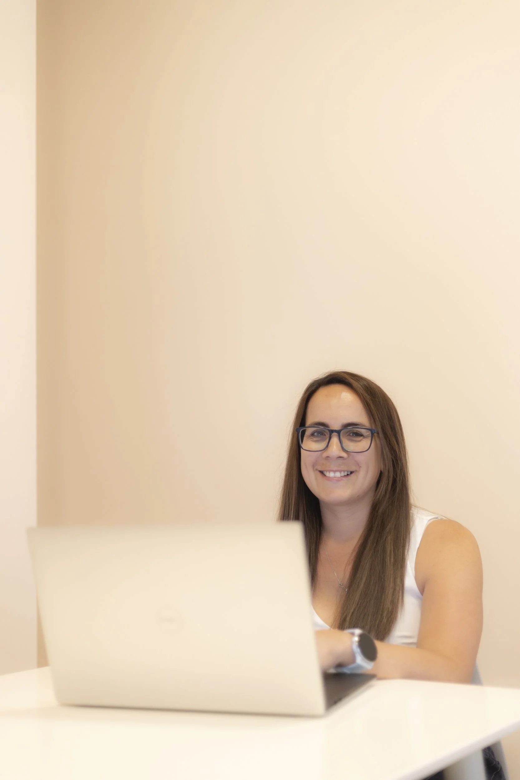 Beckie, a woman with brown hair, wearing a white shirt smiles at the camera.