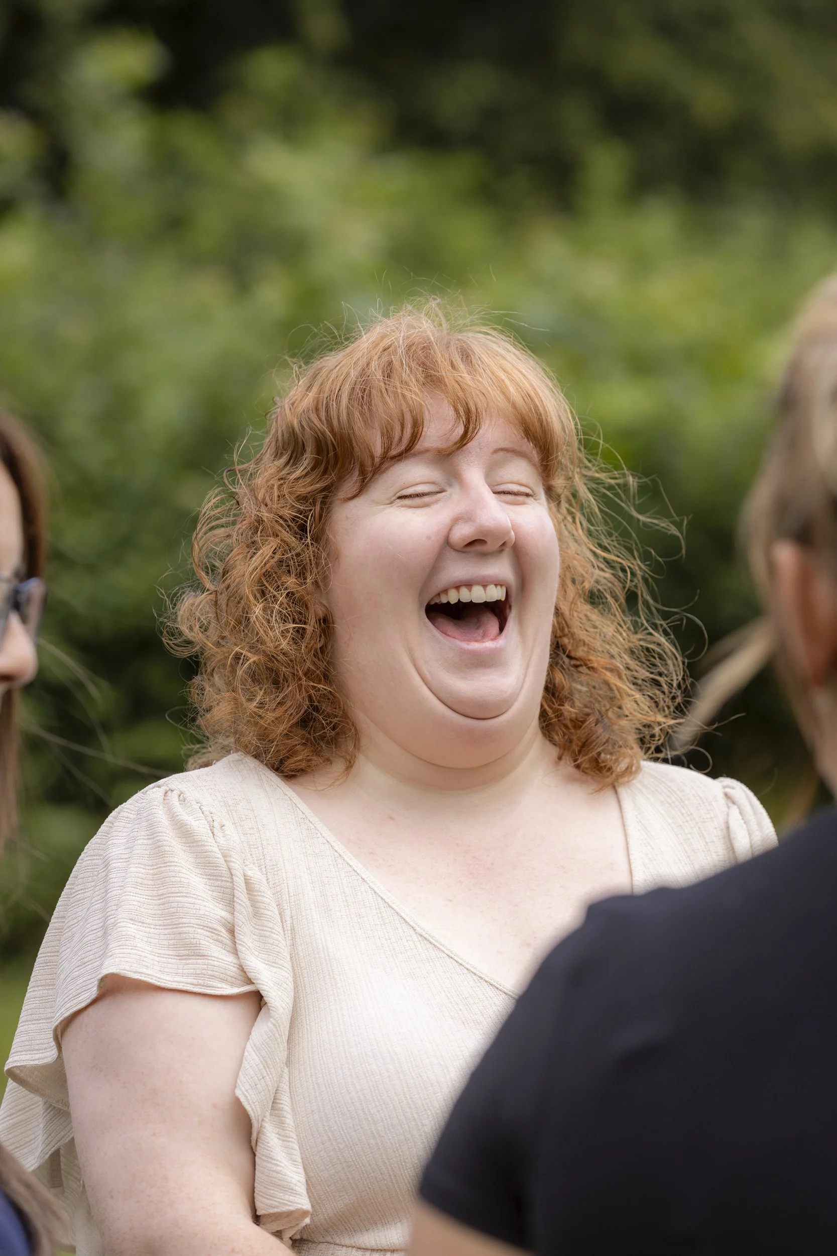 Holly, a woman with ginger hair laughs joyfully.