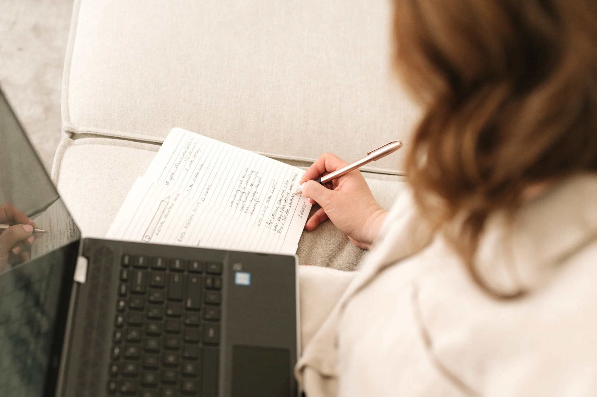 Close up image of a lady writing notes in a notebook.