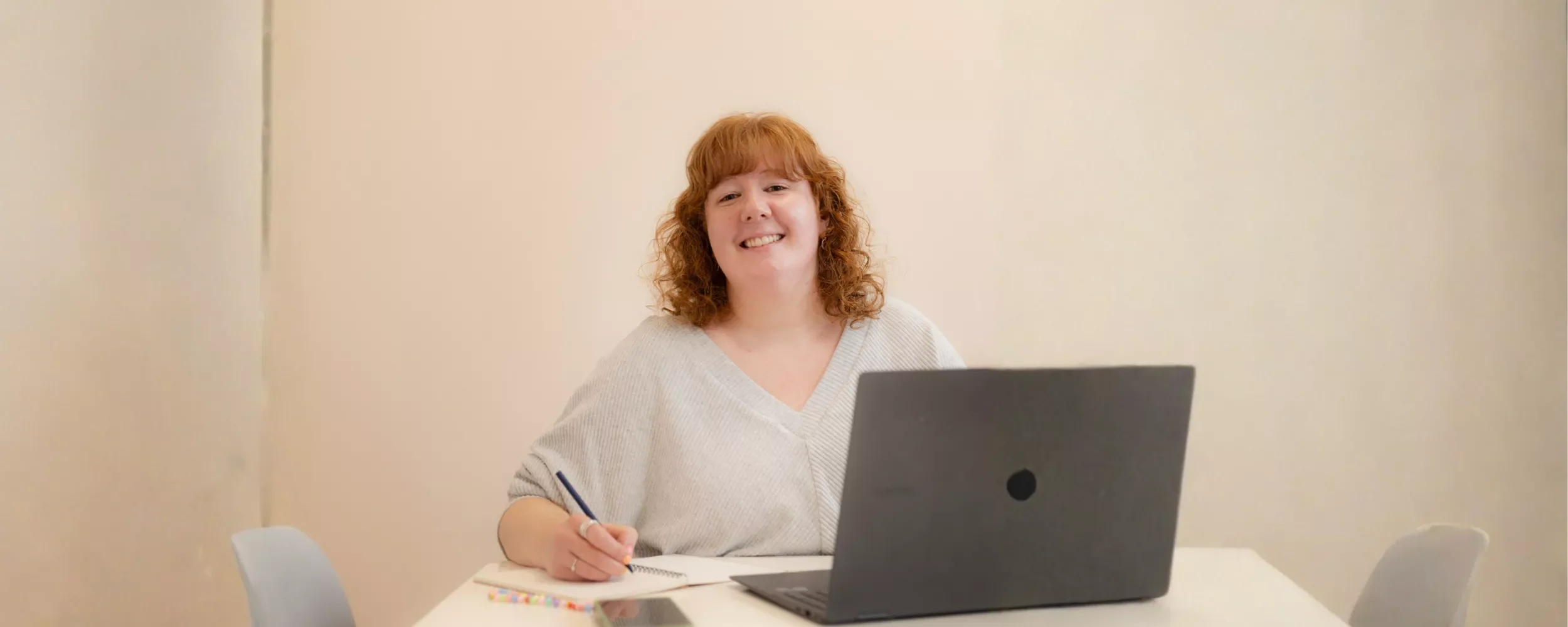 Holly, a lady with wavy ginger hair, smiles warmly at the camera.
