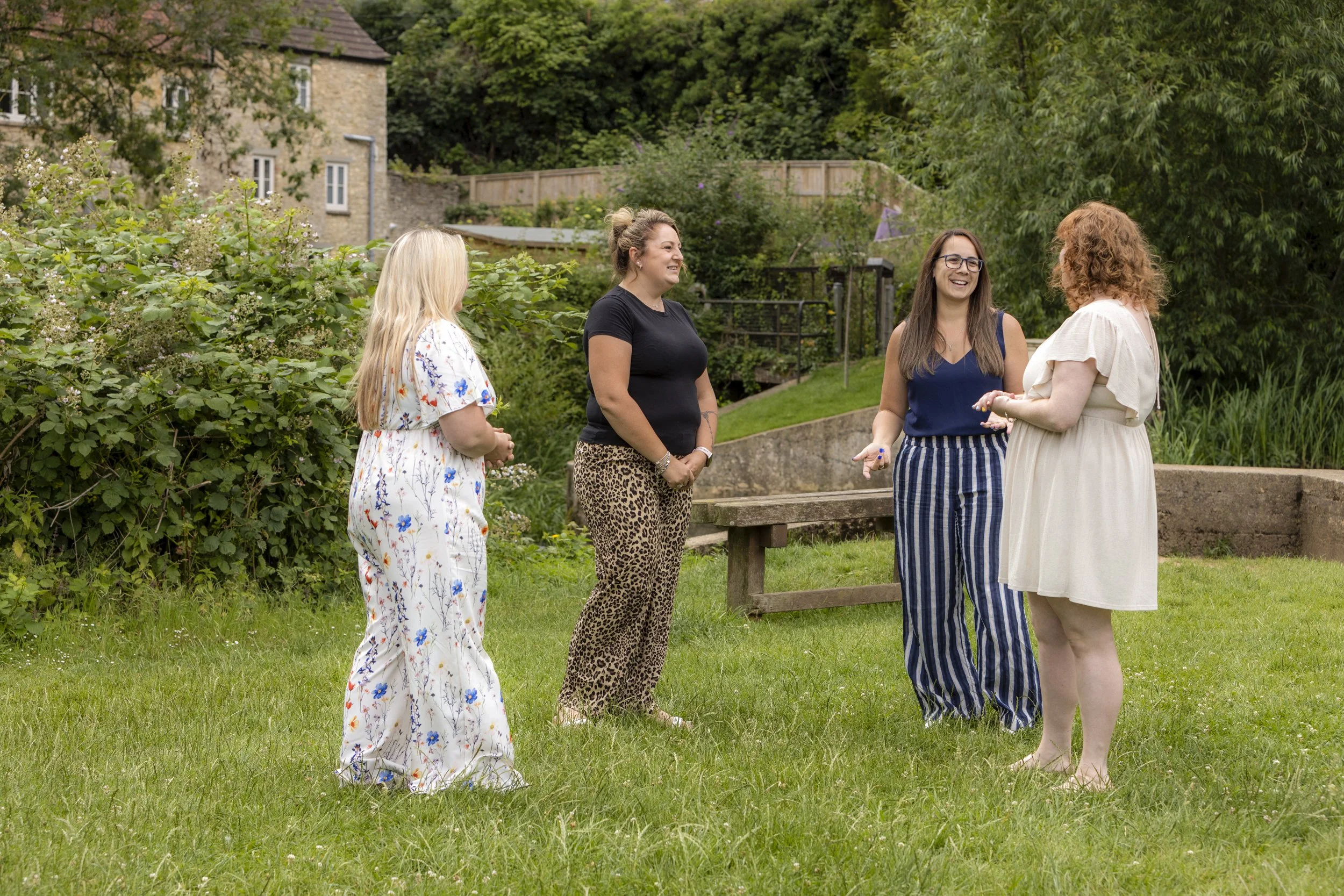 A group of four women stand in a circle talking with each other.