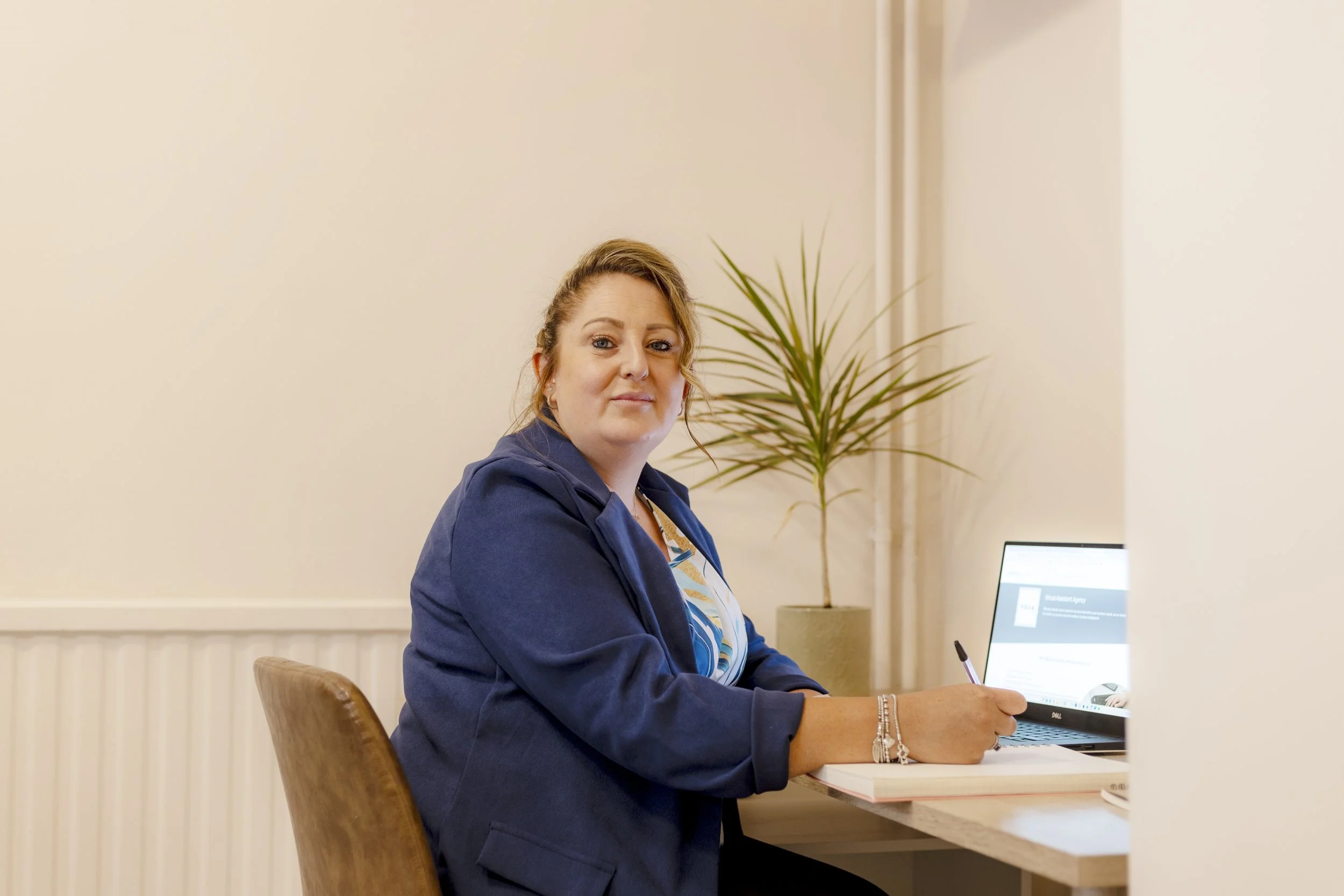 Christie, a lady with blonde hair who is wearing a blue suit, smiles at the camera.