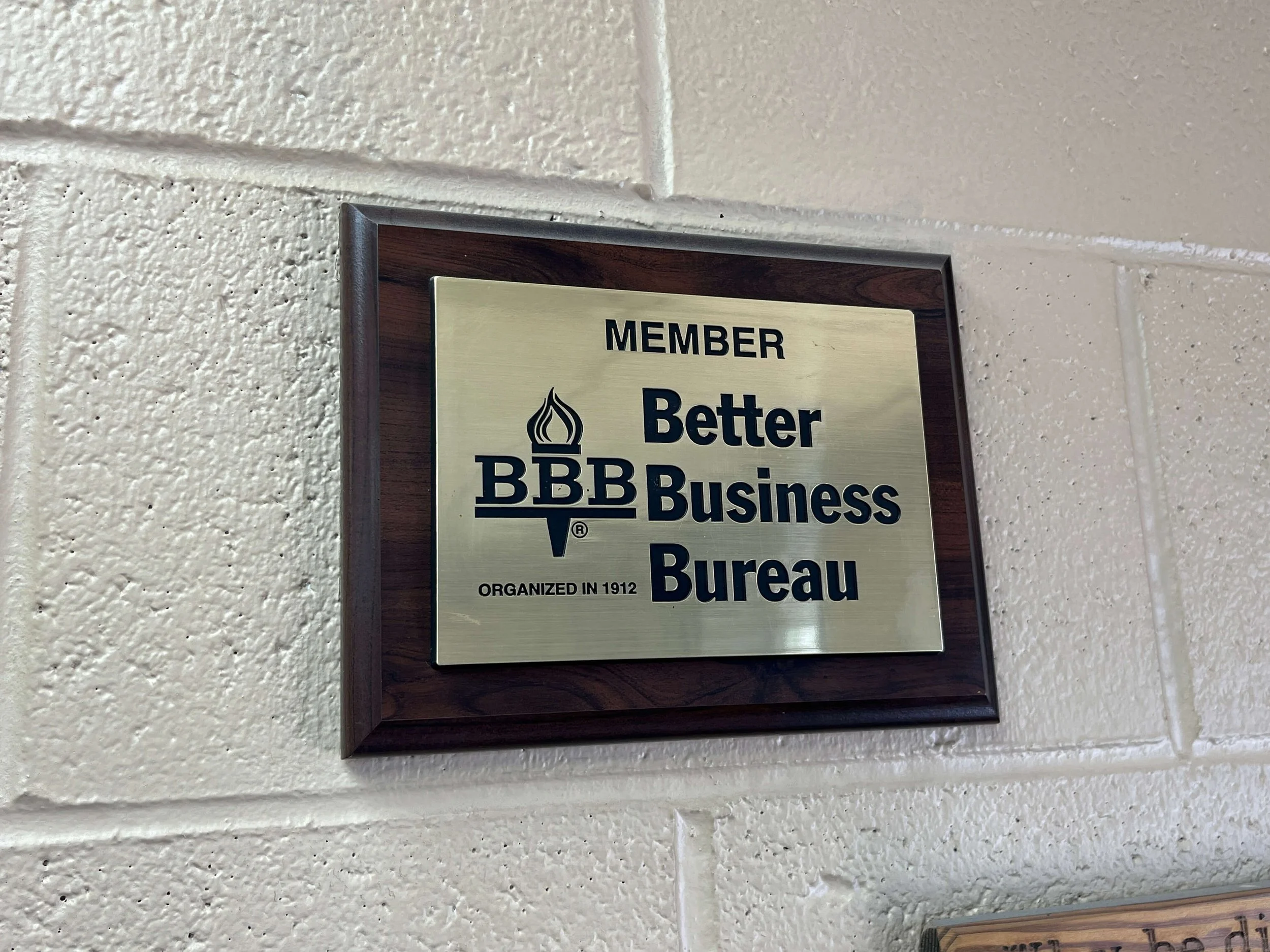 Plaque indicating membership in the Better Business Bureau, mounted on a wall.
